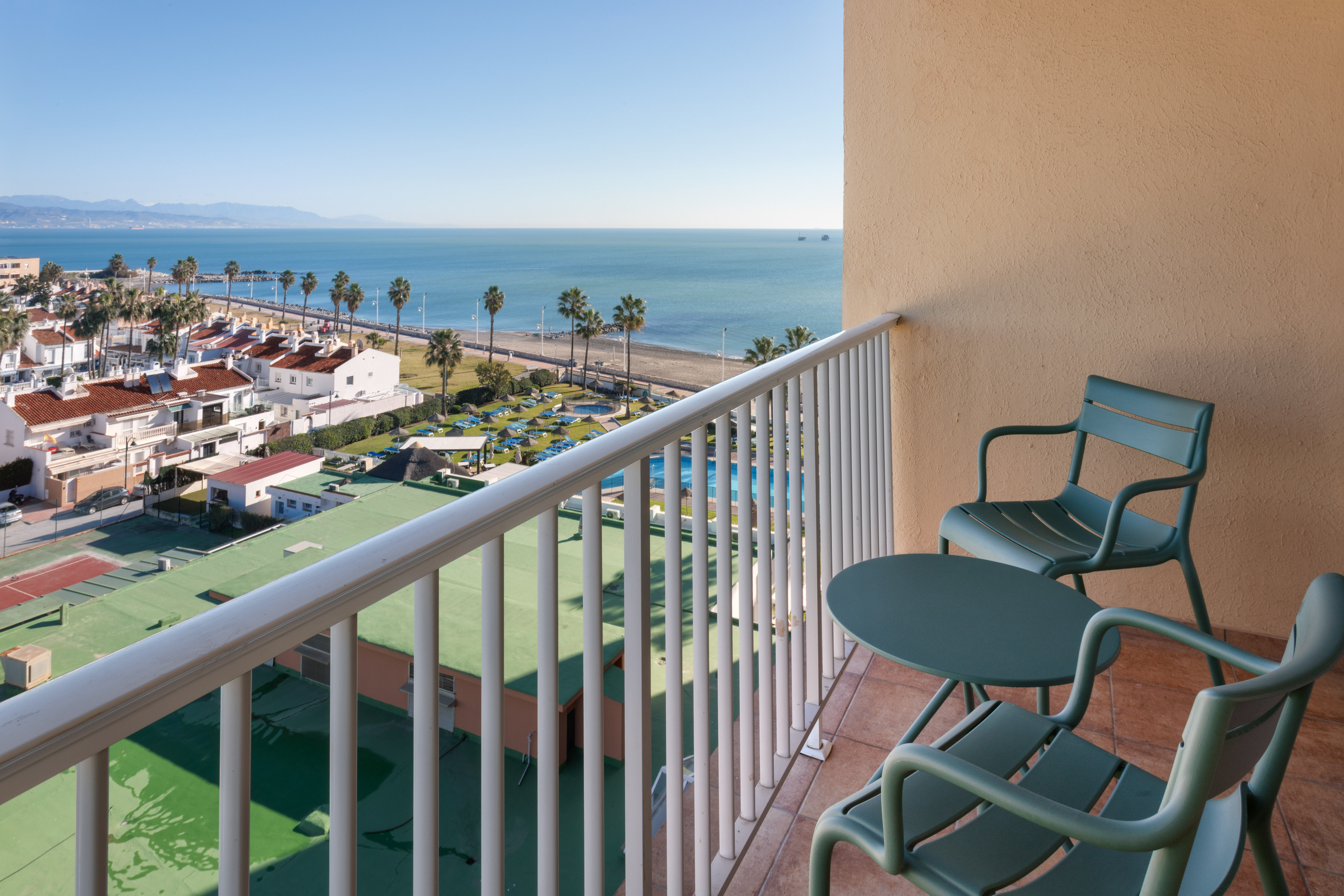 a balcony with chairs and a beach and water