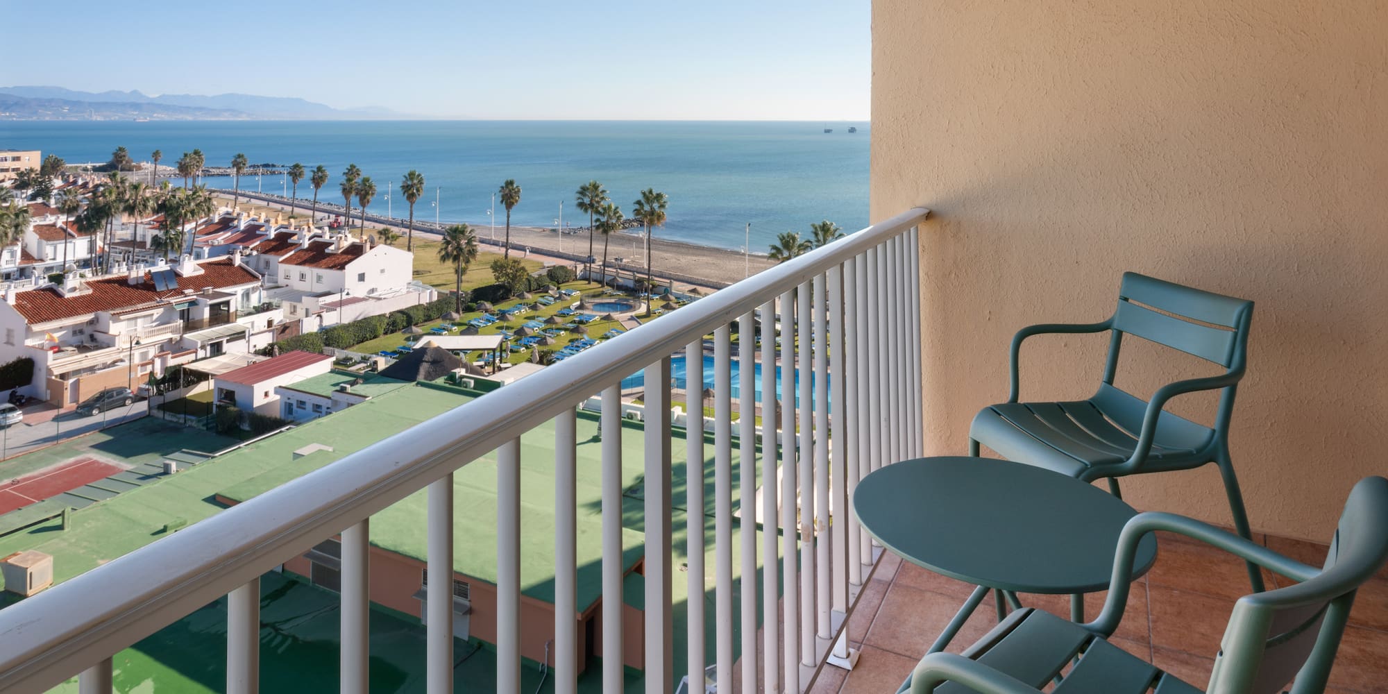 a balcony with chairs and a beach and water