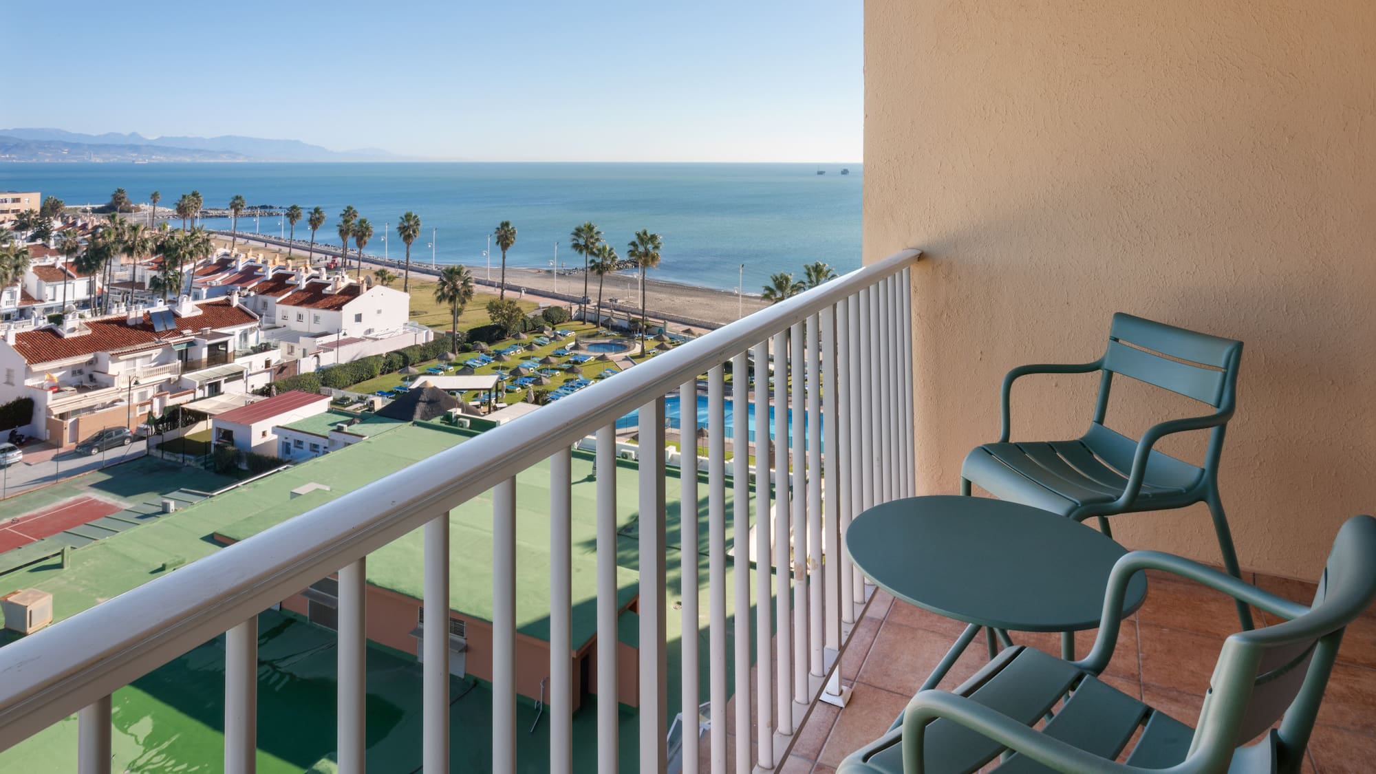 a balcony with chairs and a beach and water