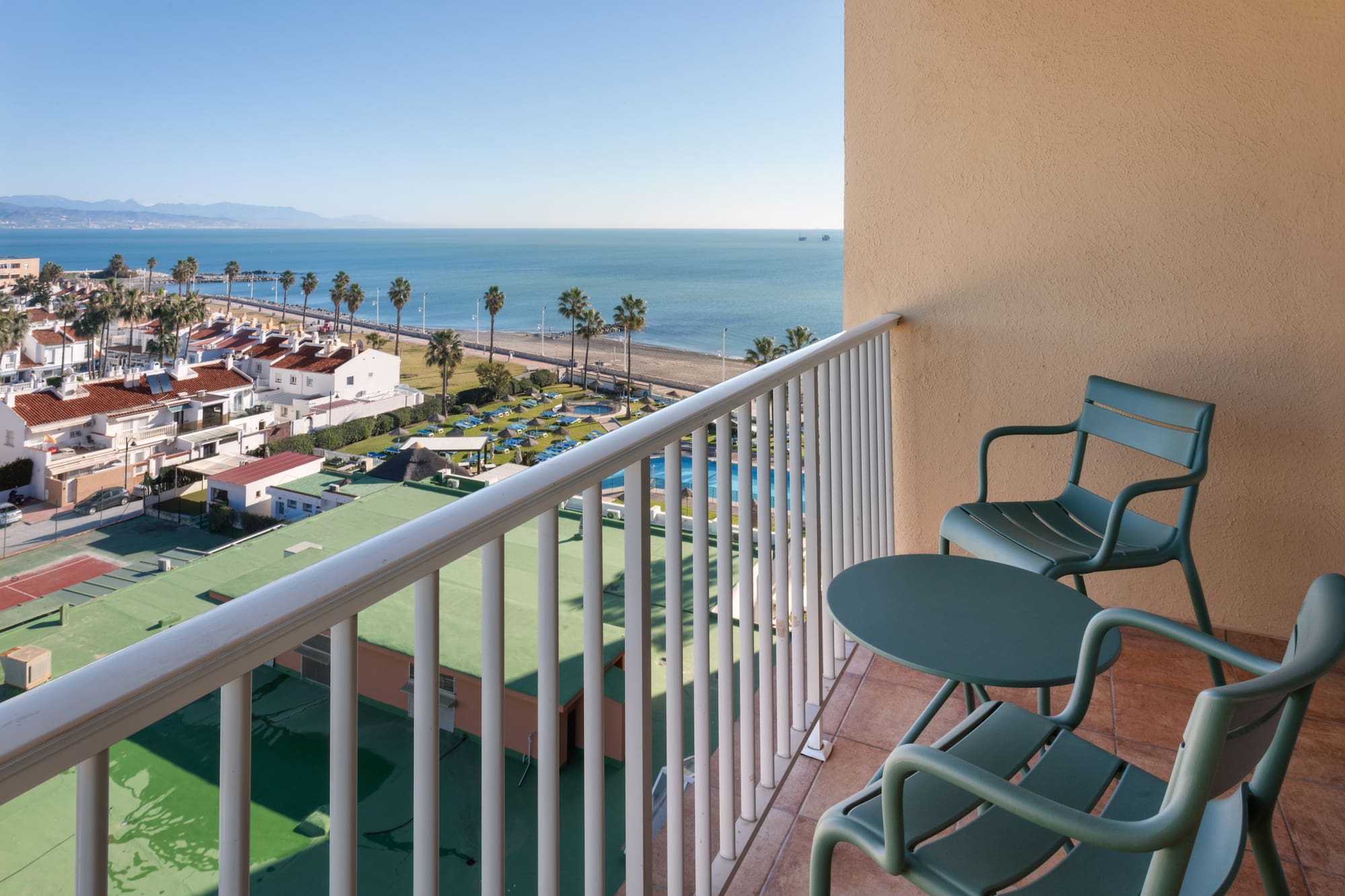 a balcony with chairs and a beach and water