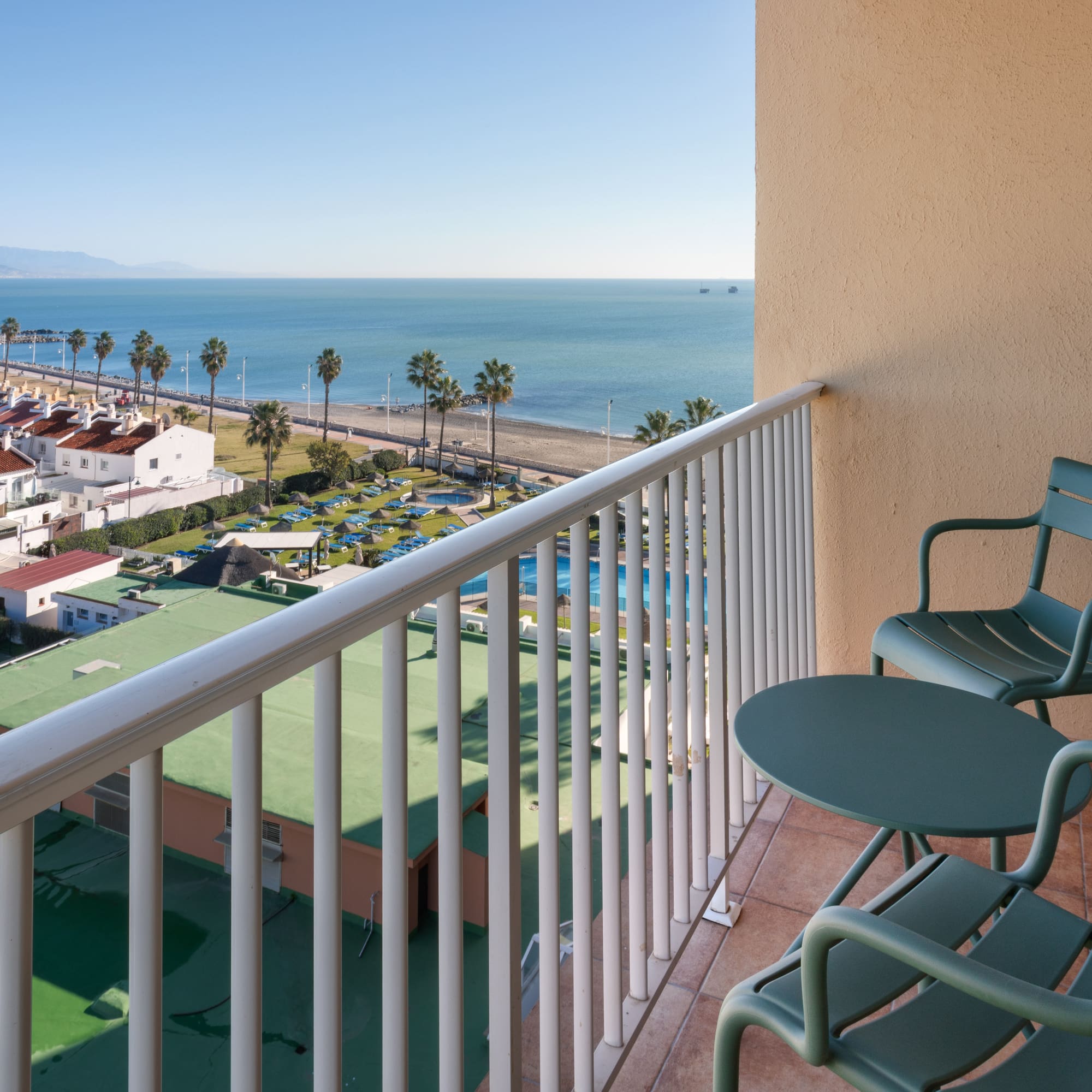 a balcony with chairs and a beach and water