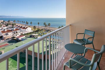 a balcony with chairs and a beach and water