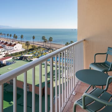 a balcony with chairs and a beach and water
