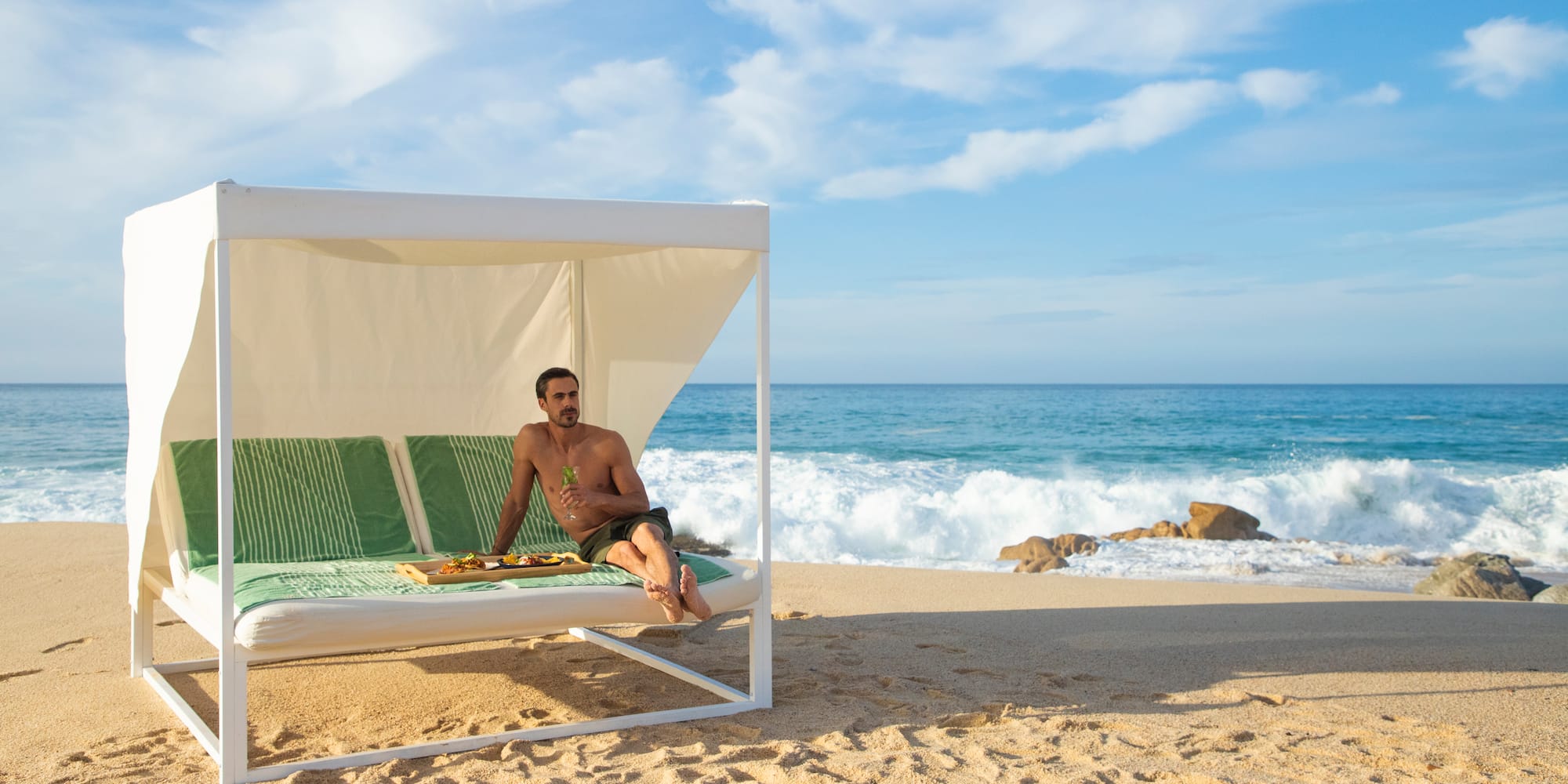 a man sitting on a bed on a beach