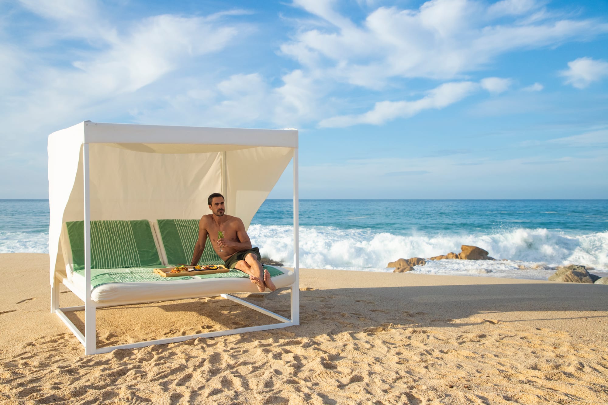 a man sitting on a bed on a beach