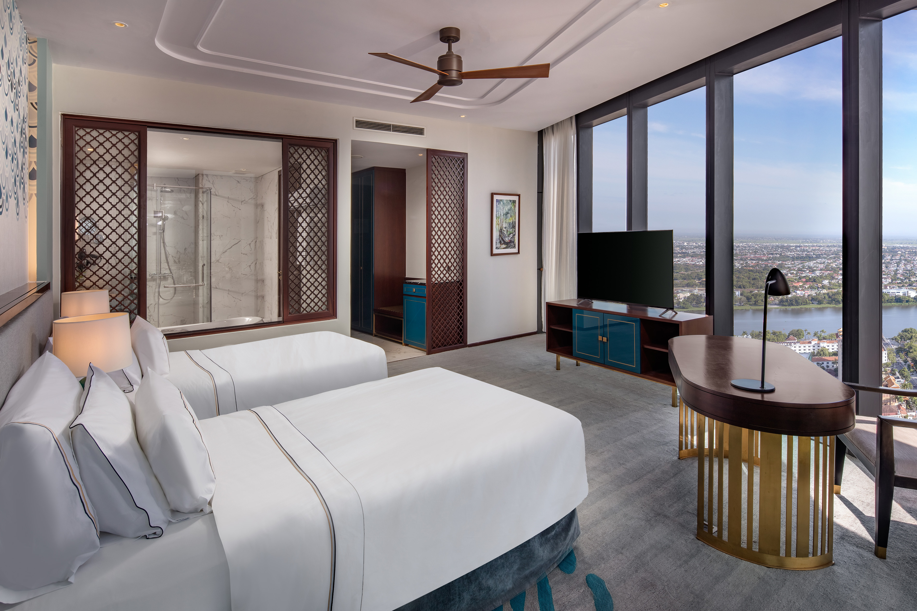 Contemporary hotel room with twin beds, city lake view, work desk, and TV.