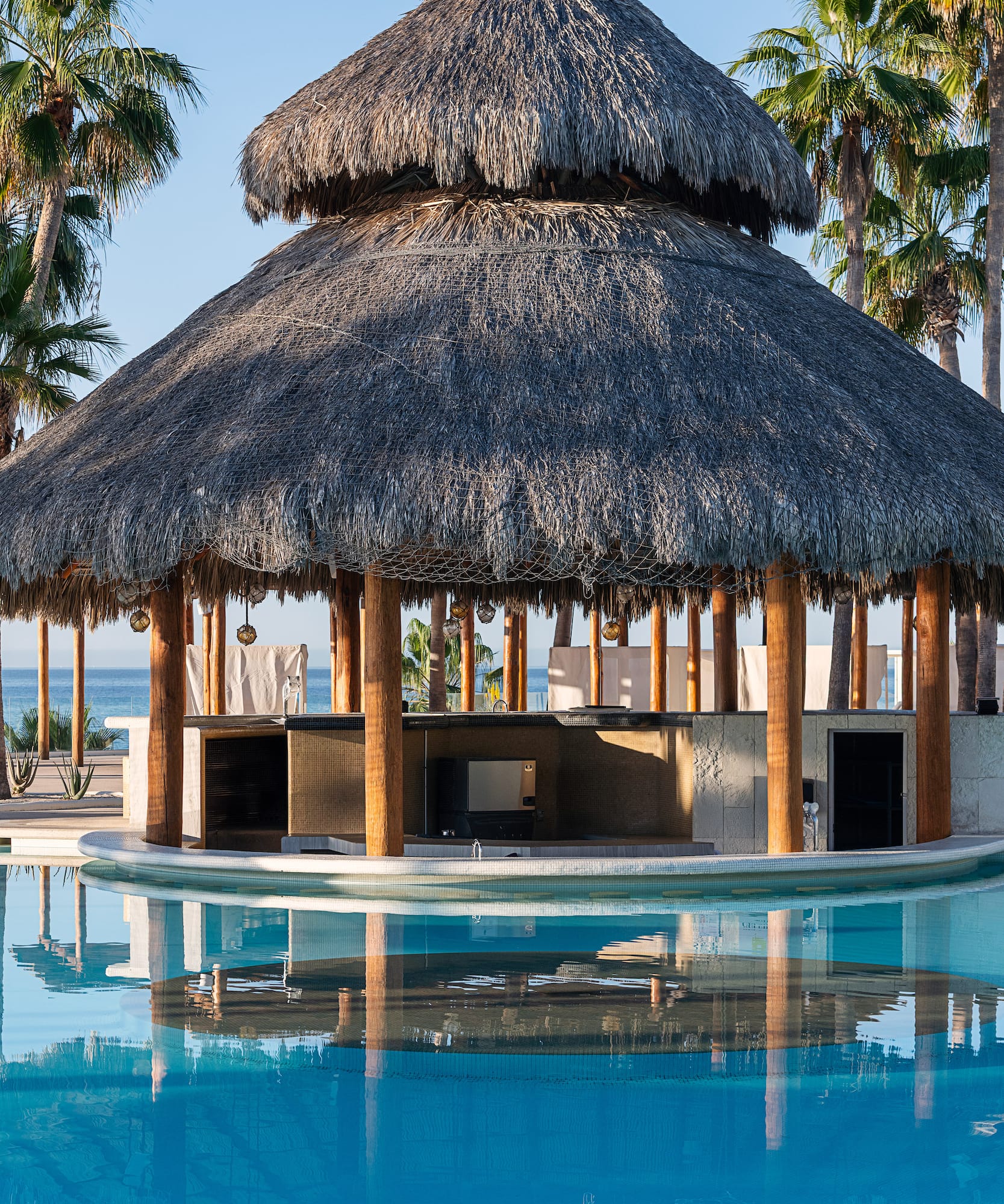 a pool with a thatched roof and a bar