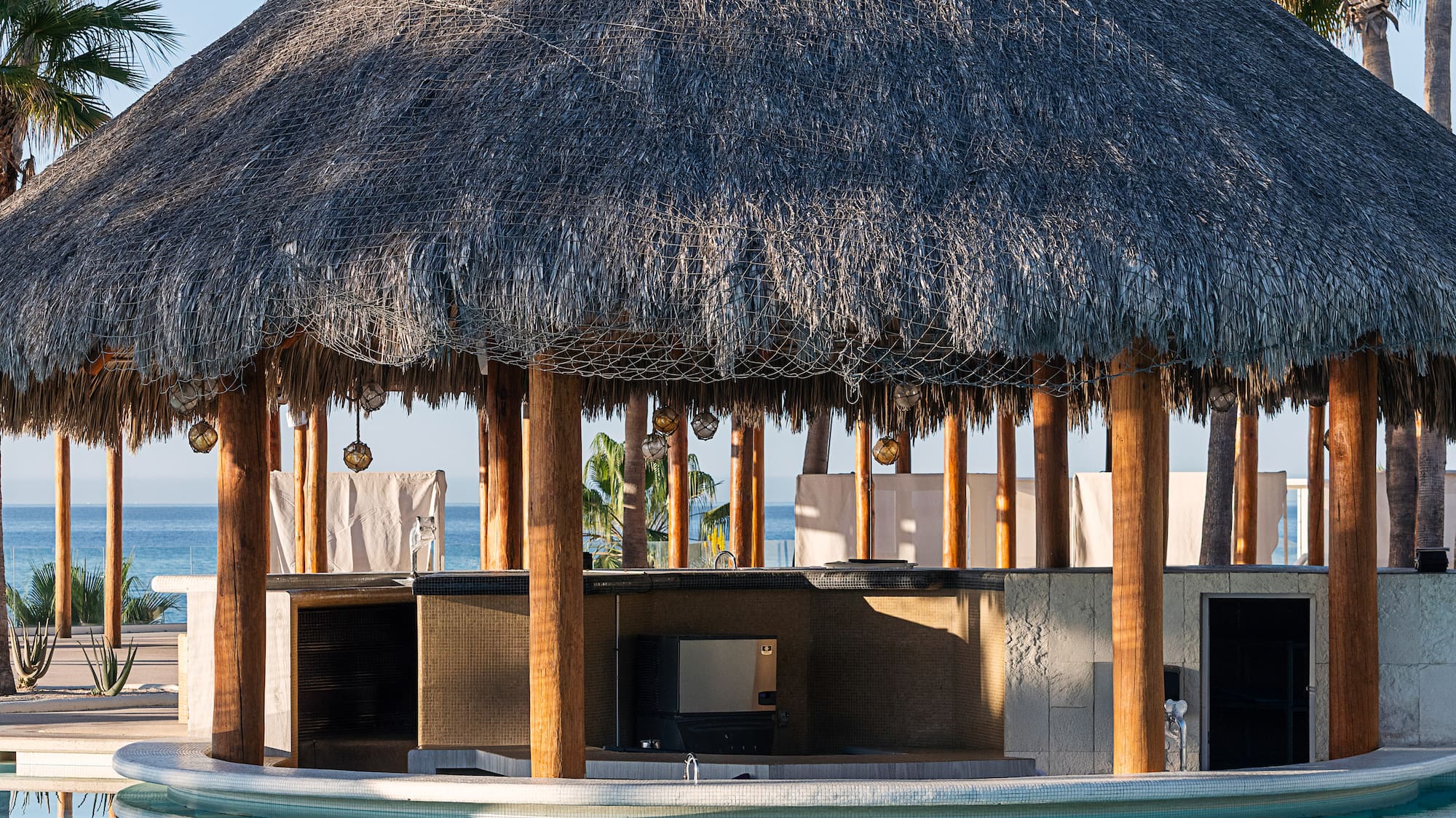 a pool with a thatched roof and a bar