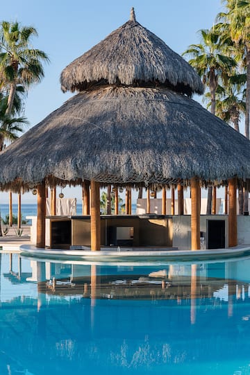 a pool with a thatched roof and a bar