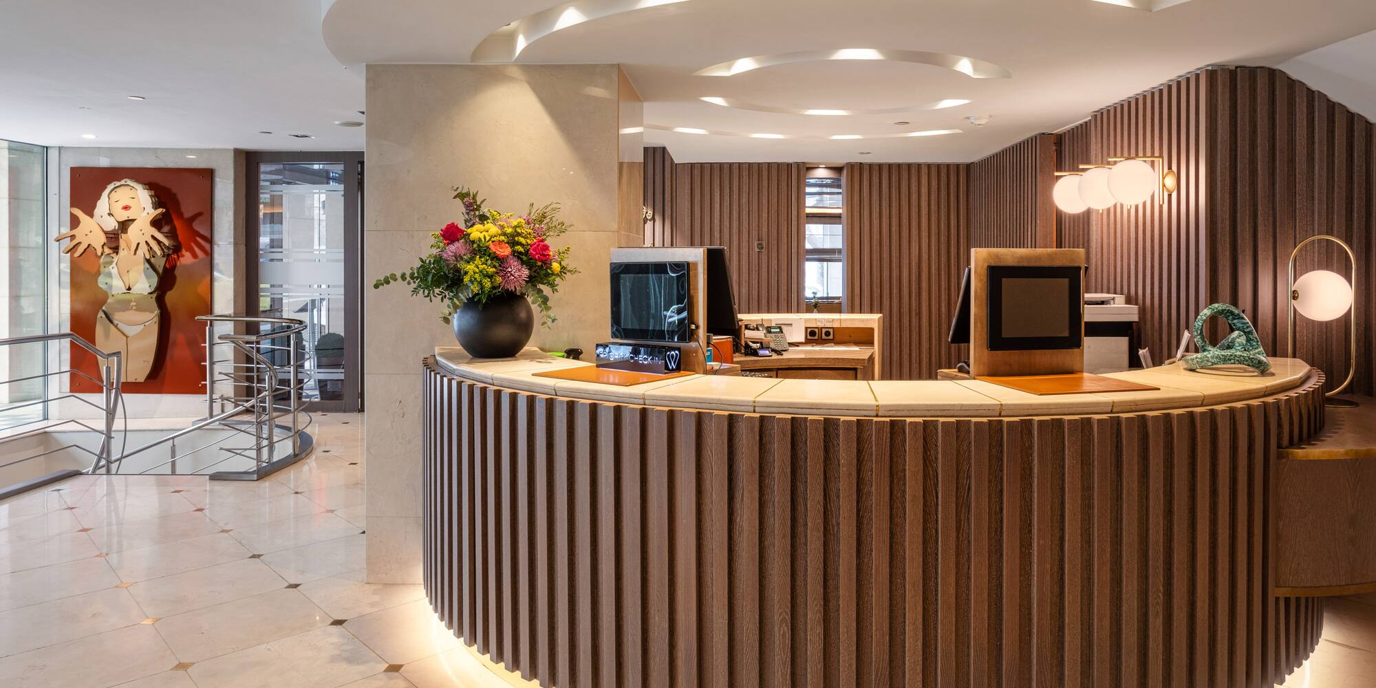 Curved wooden reception desk with backlight in a modern hotel lobby.