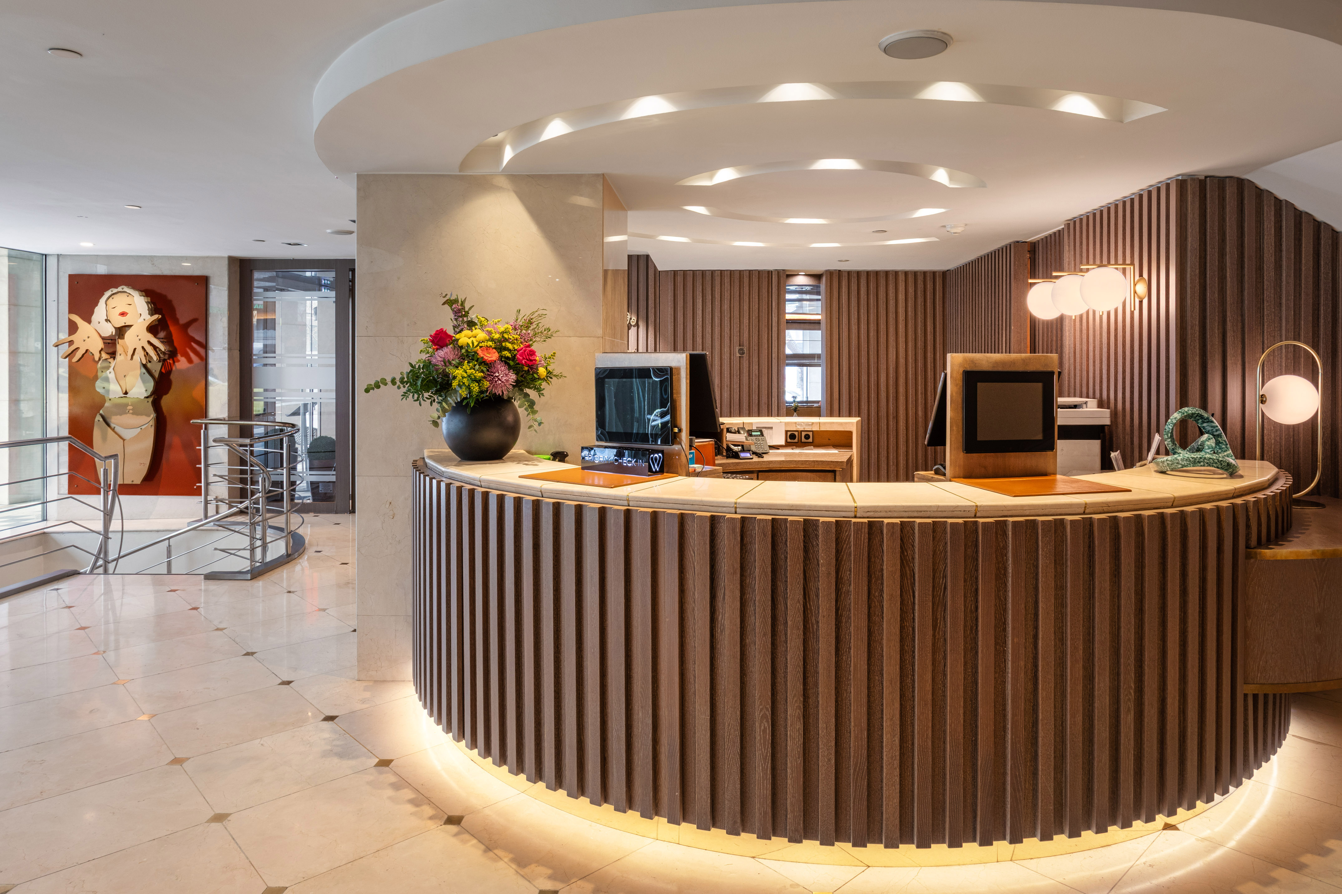 Curved wooden reception desk with backlight in a modern hotel lobby.