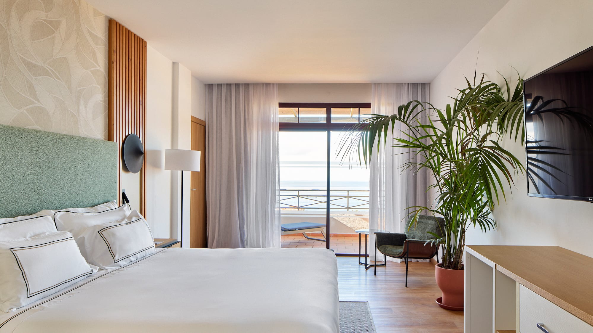 a bedroom with a large bed and a plant