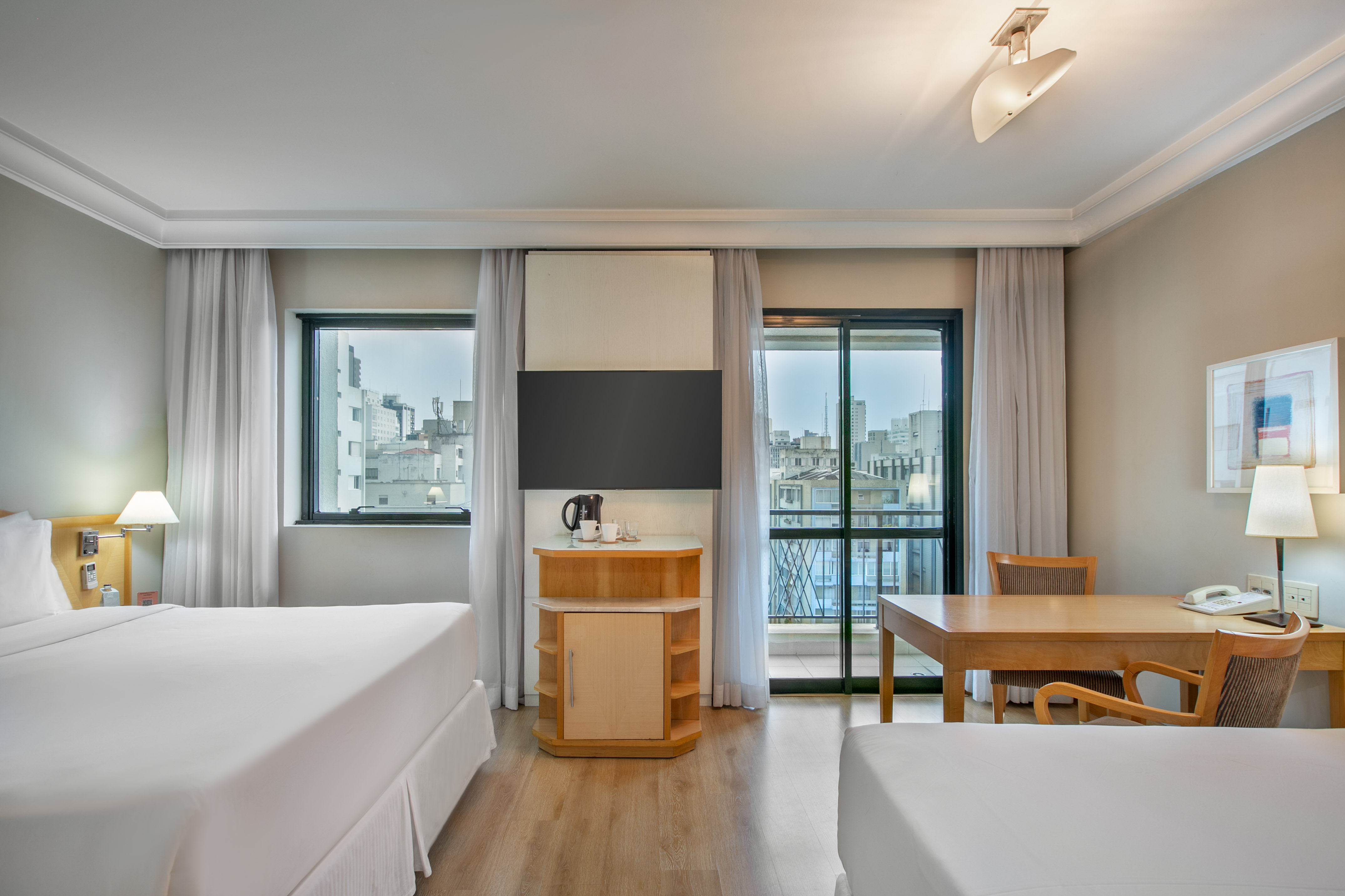Hotel guest room with two beds, desk, TV, and balcony offering city views. - The INNSiDE Triple Queen - INNSiDE São Paulo Higienópolis, Sao Paulo