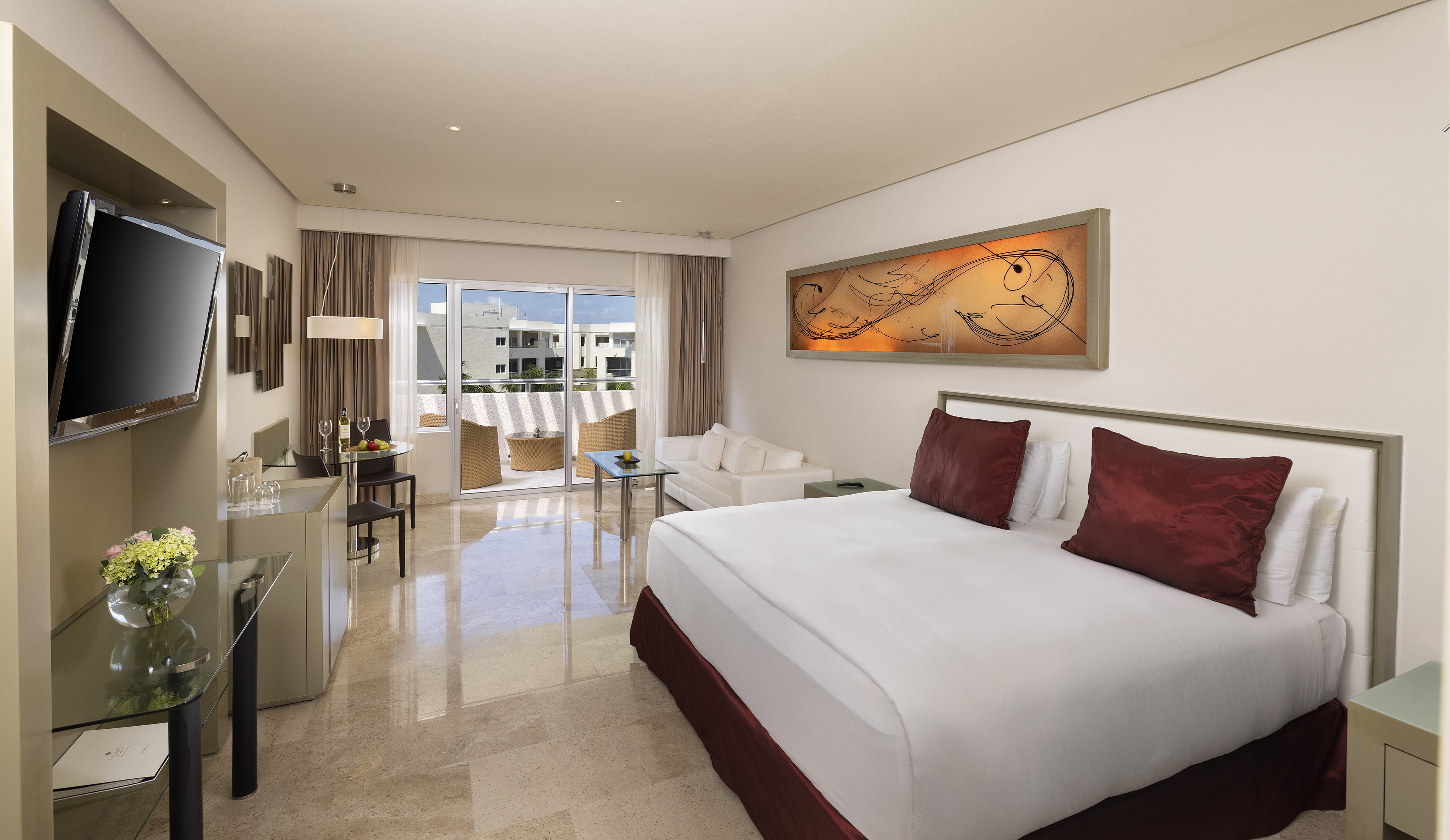 Resort suite with king bed, living area, dining table, and private balcony.
