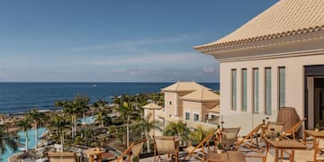 a deck chairs and a building with a body of water in the background