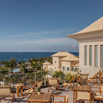 a deck chairs and a building with a body of water in the background