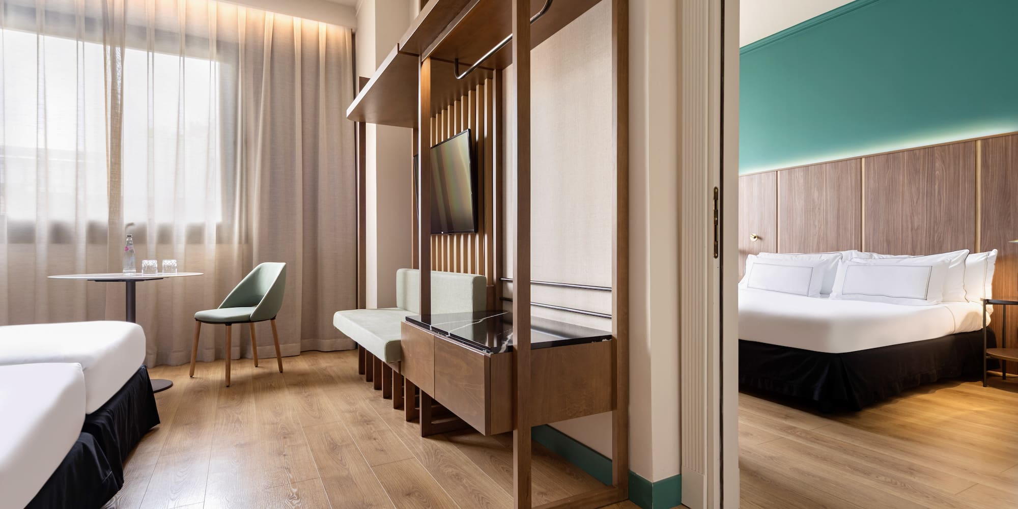 Modern hotel suite with twin beds, sitting area, and separate bedroom.