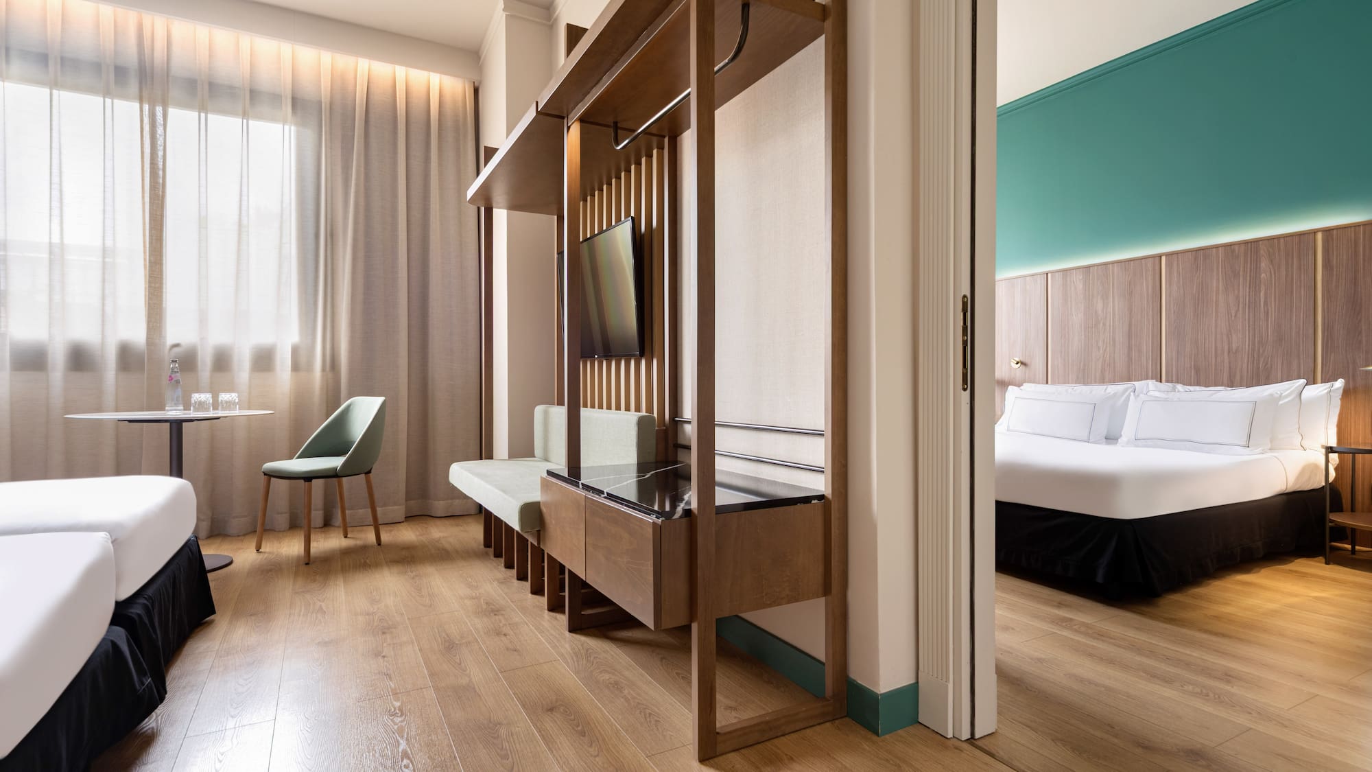 Modern hotel suite with twin beds, sitting area, and separate bedroom.