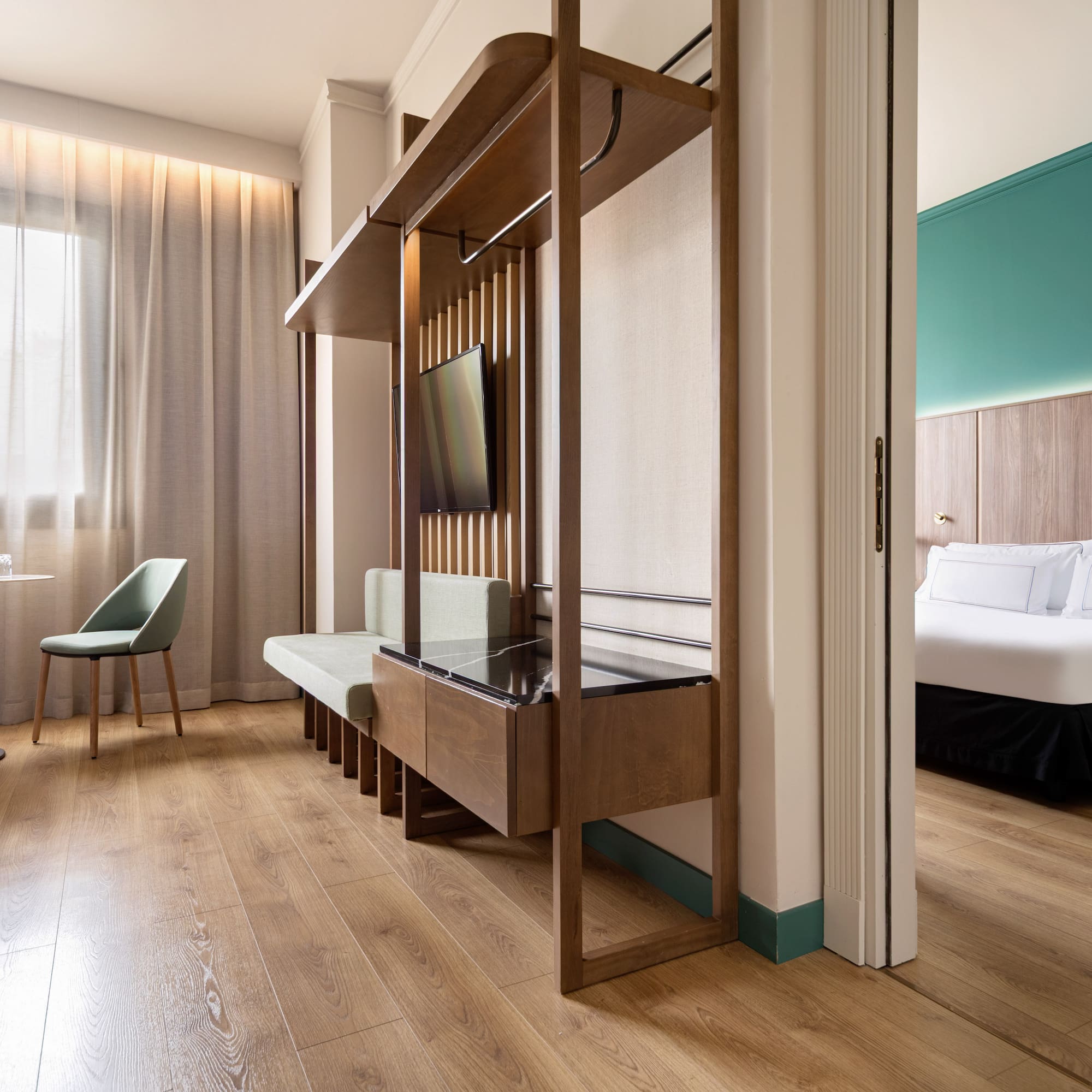 Modern hotel suite with twin beds, sitting area, and separate bedroom.