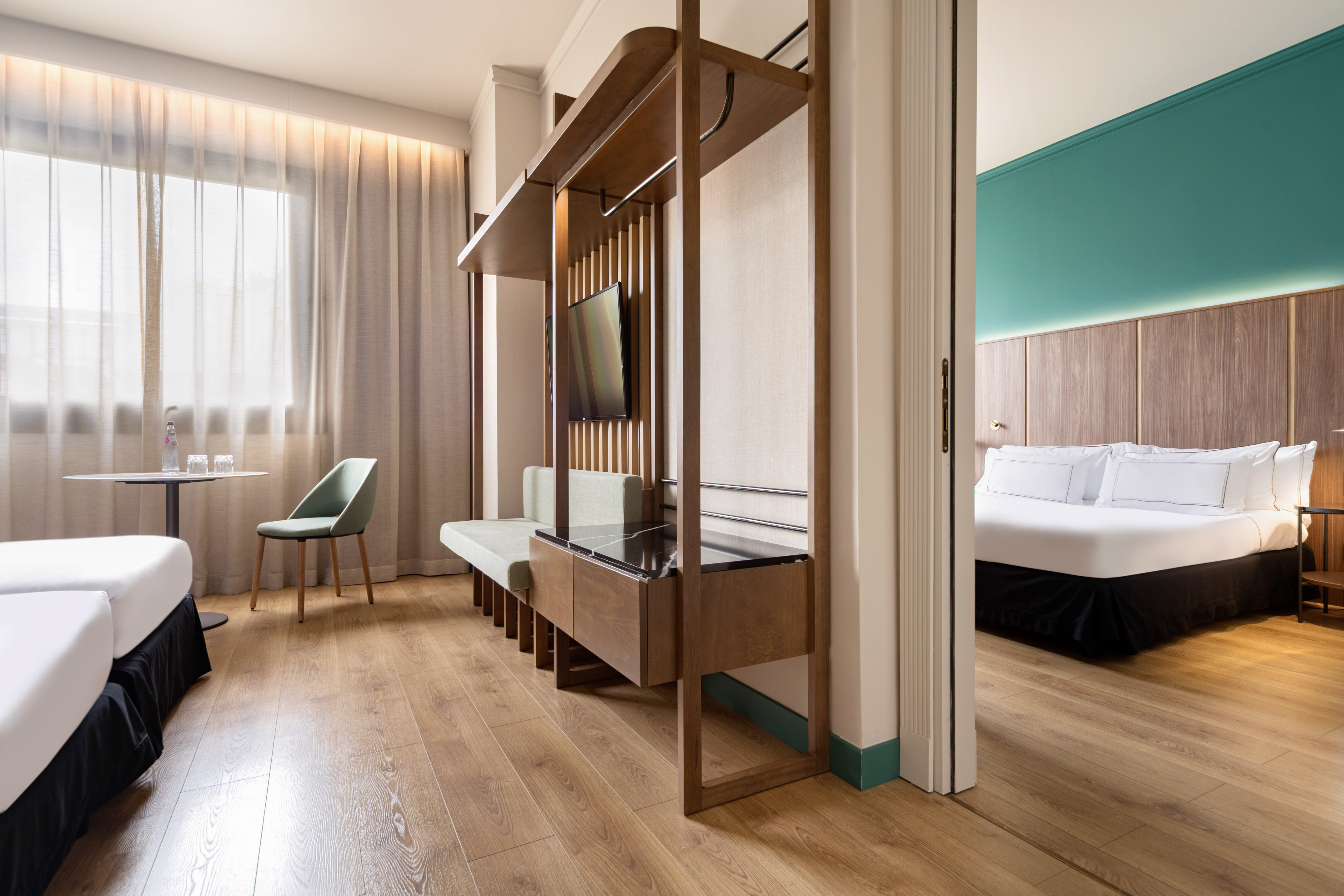 Modern hotel suite with twin beds, sitting area, and separate bedroom.