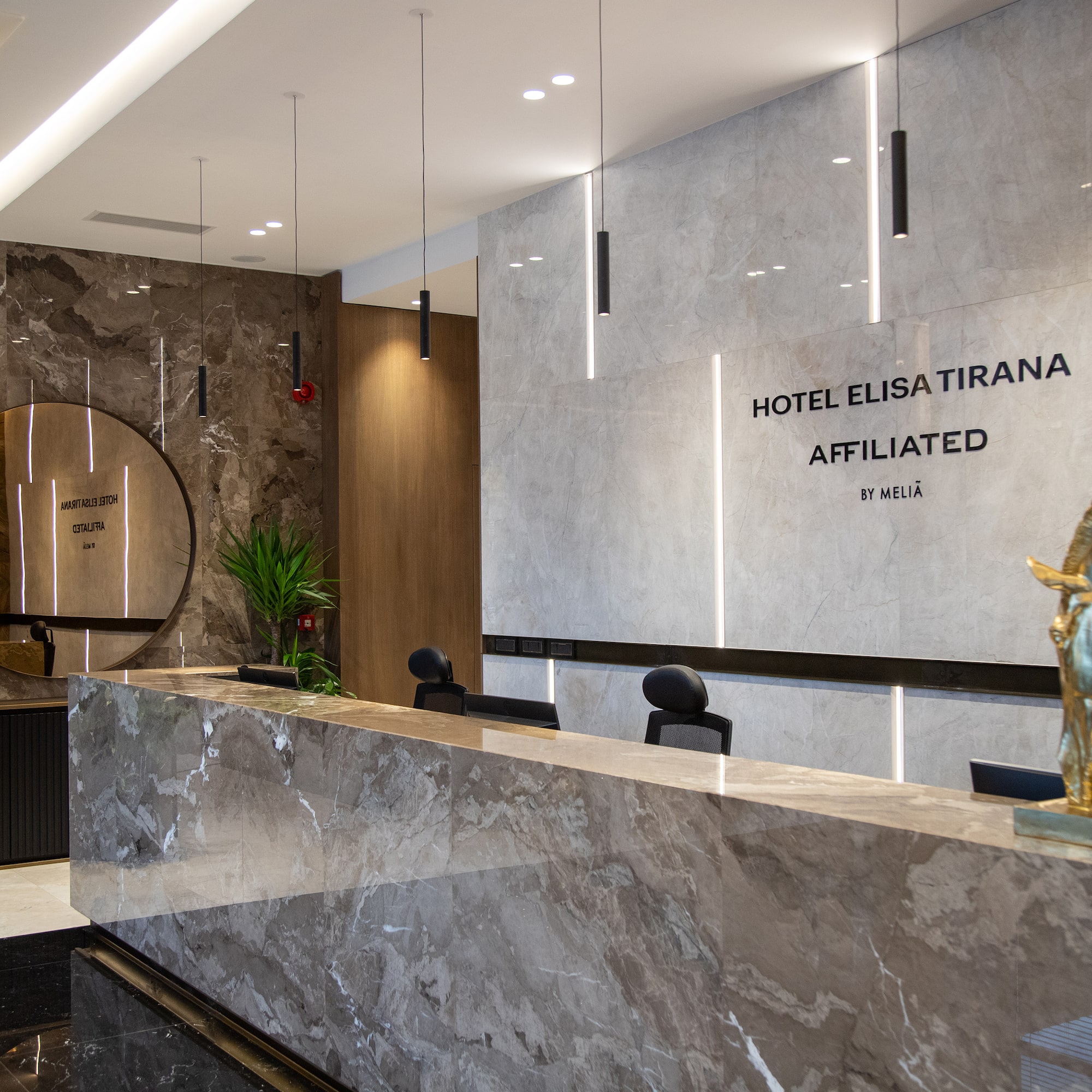 Luxurious Hotel Elisa Tirana lobby with marble reception desk and modern decor.
