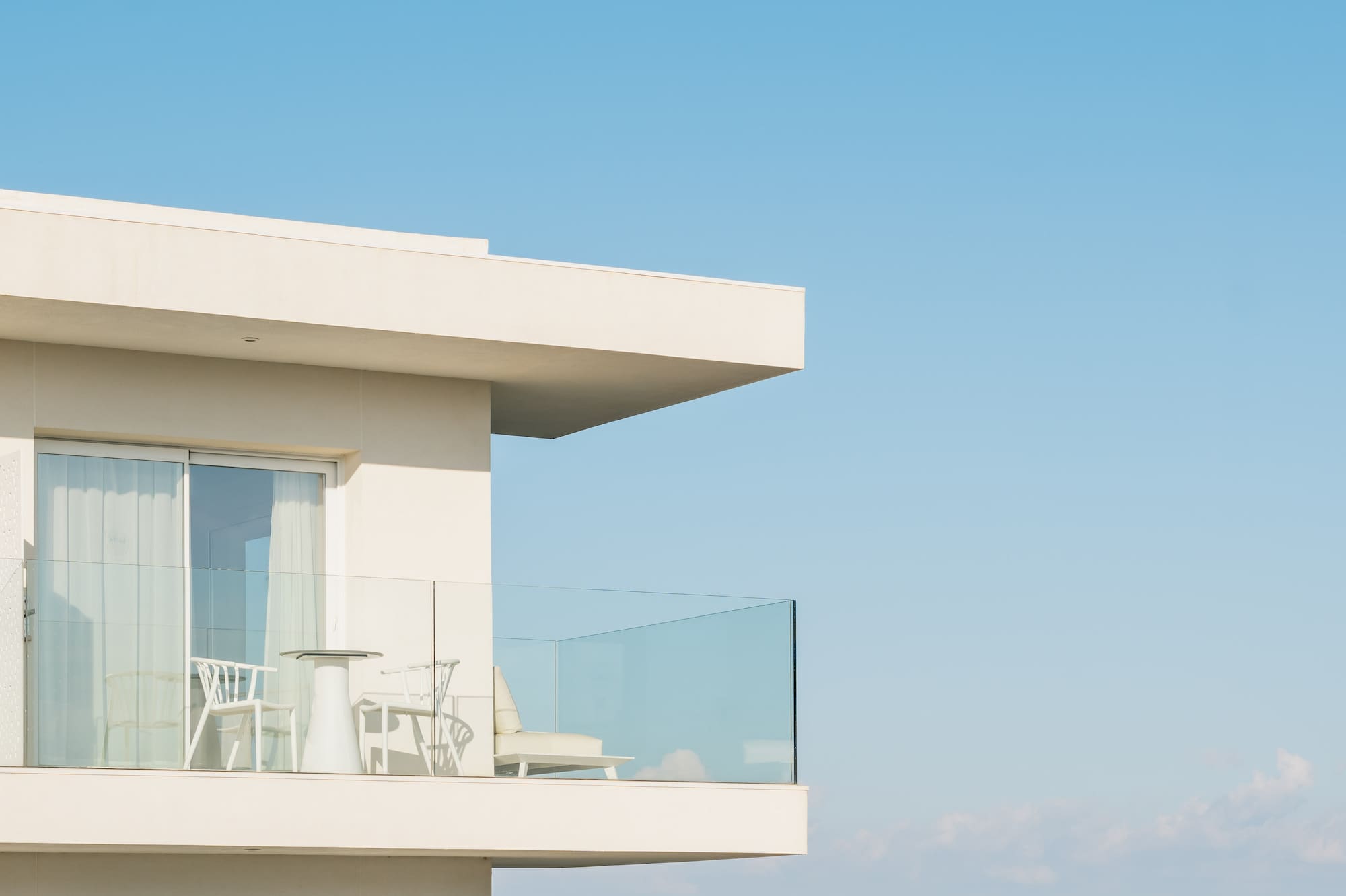 a white building with a glass balcony overlooking the ocean