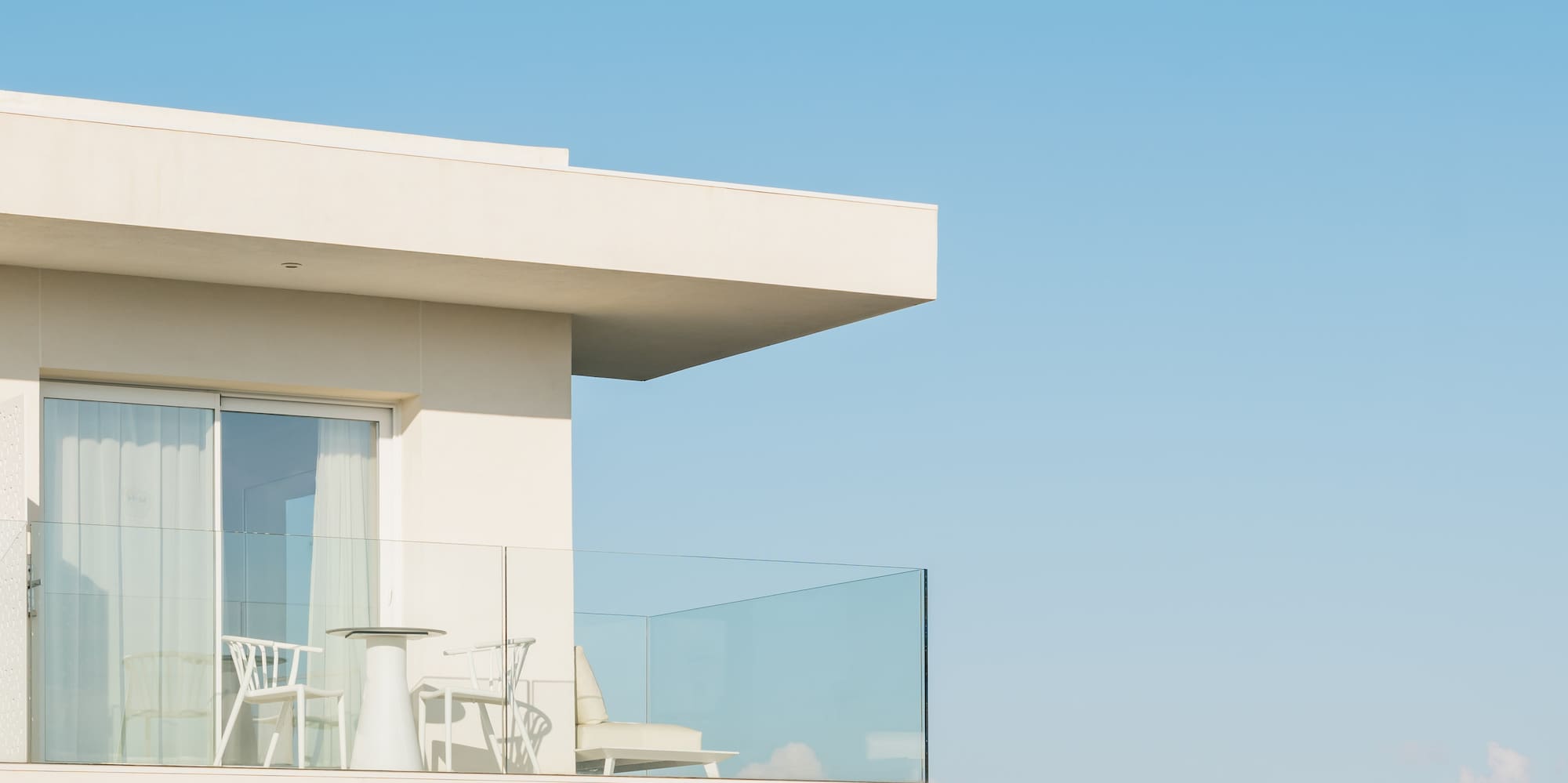 a white building with a glass balcony overlooking the ocean