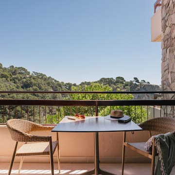 a table and chairs on a balcony overlooking trees