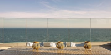 a table with chairs and a view of the ocean
