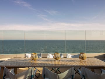 a table with chairs and a view of the ocean