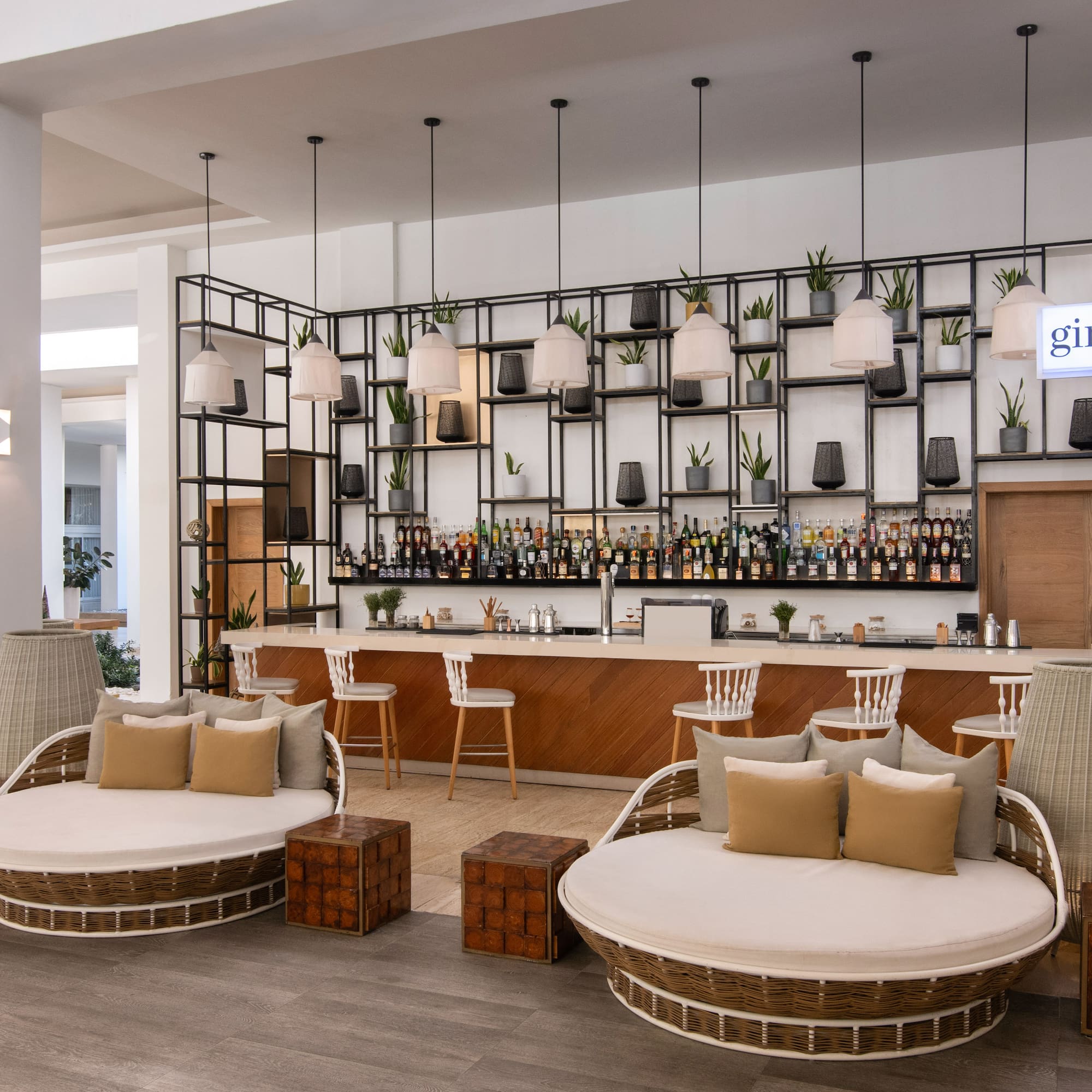 Modern hotel bar 'Gin Ger' with circular lounge chairs and drinks display.