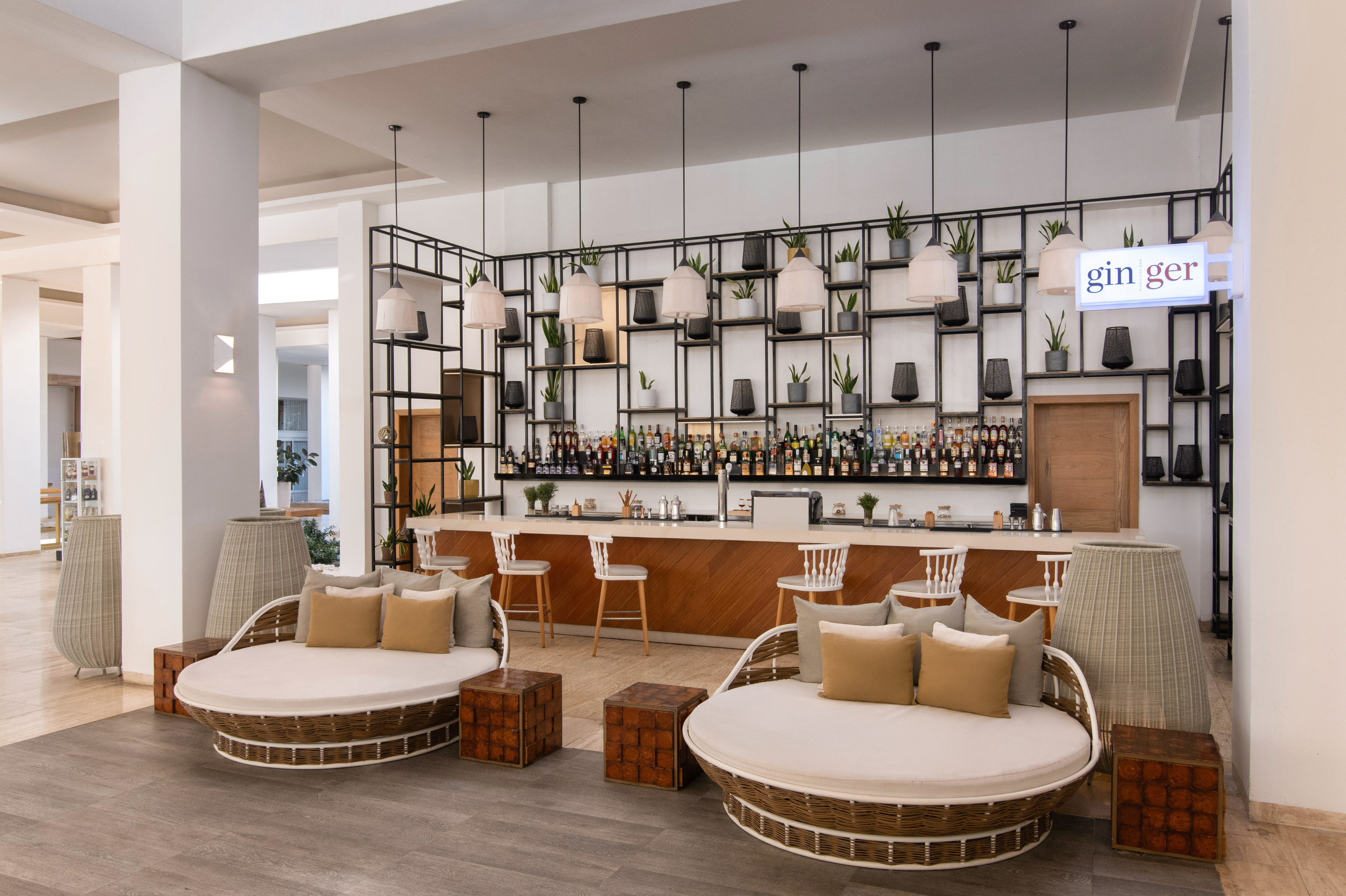 Modern hotel bar 'Gin Ger' with circular lounge chairs and drinks display.