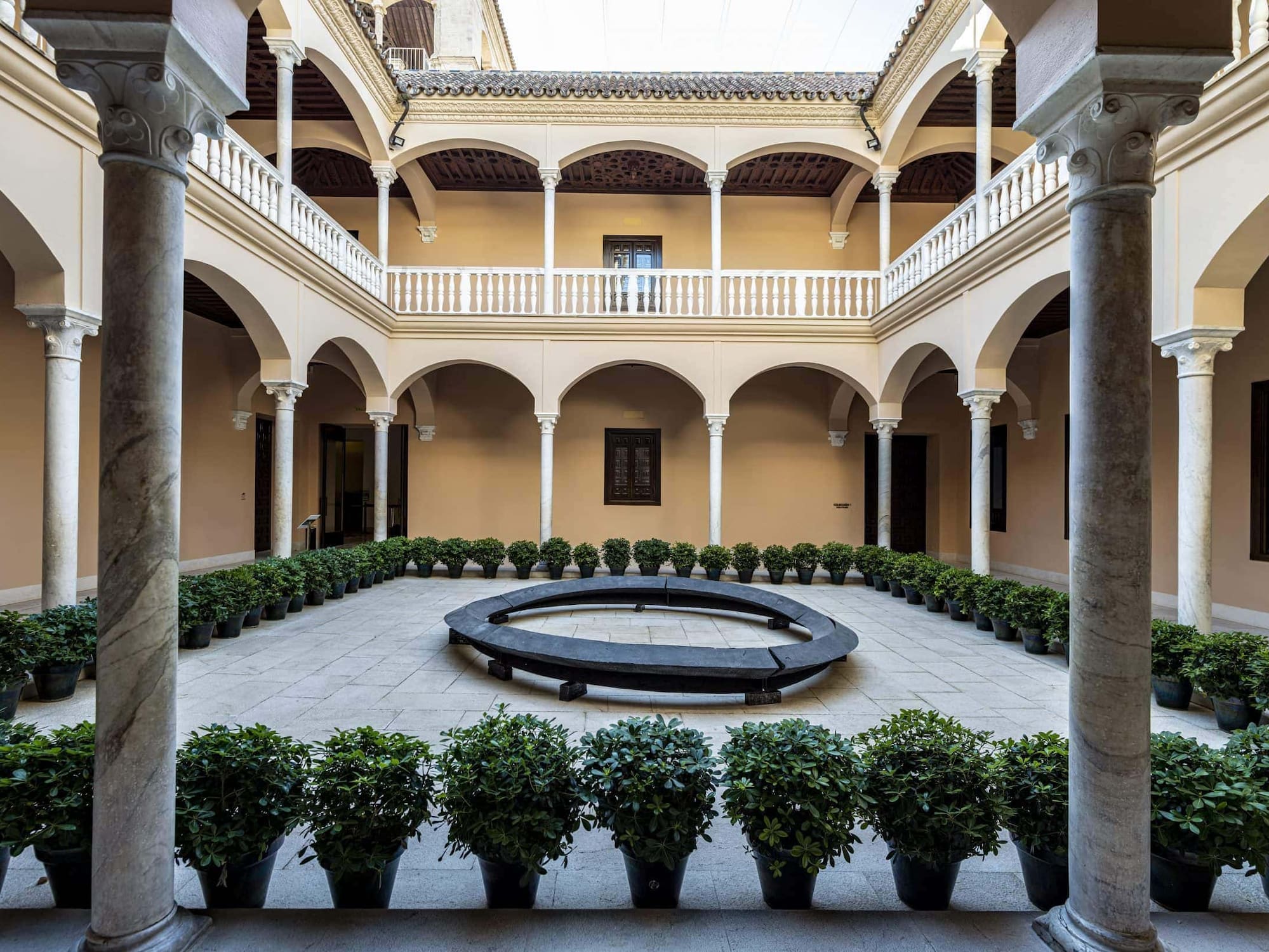 a courtyard with a circular bench and potted plants