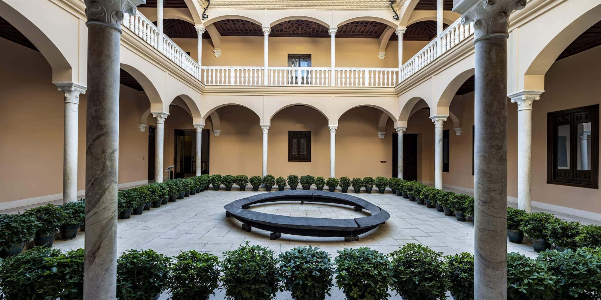 a courtyard with a circular bench and potted plants