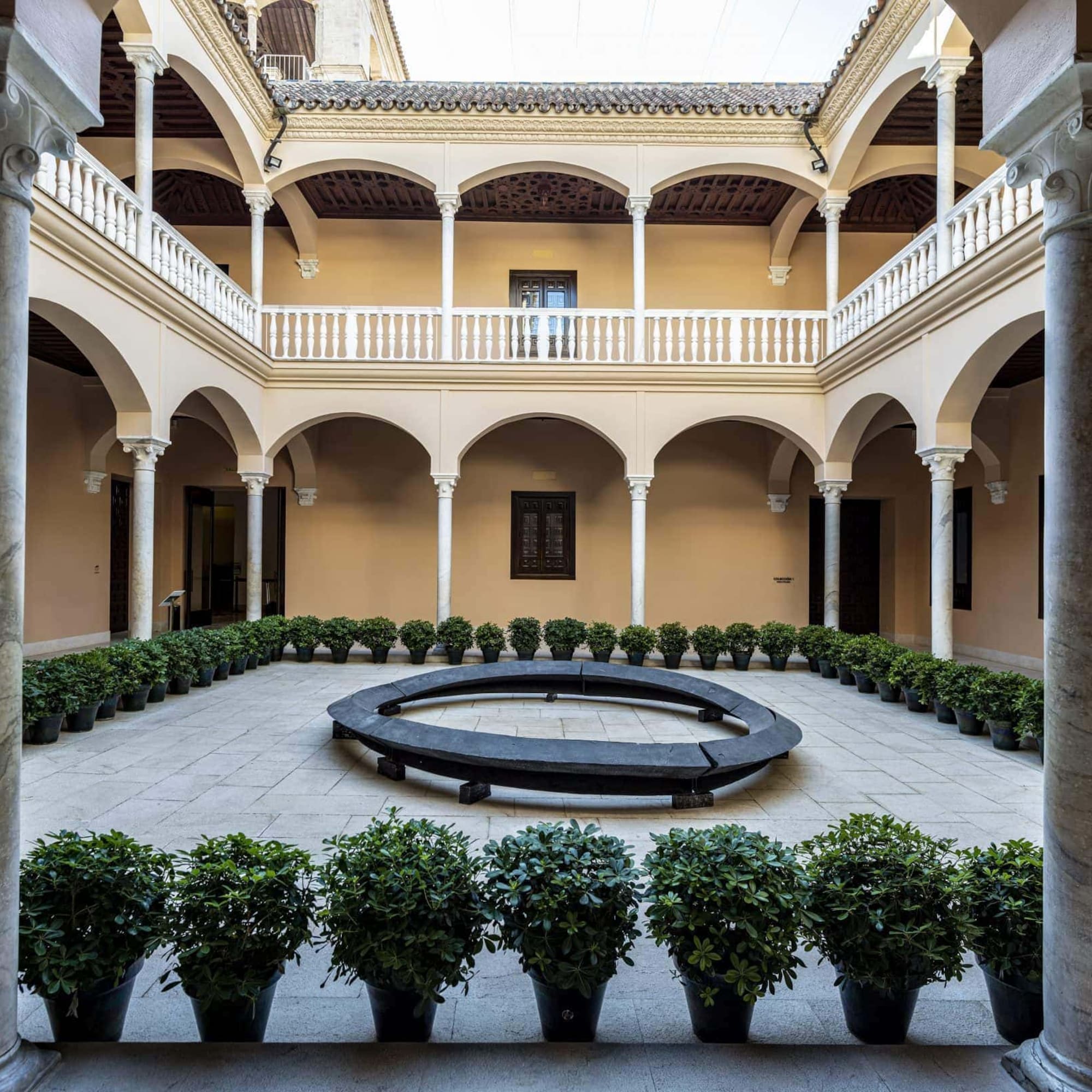 a courtyard with a circular bench and potted plants