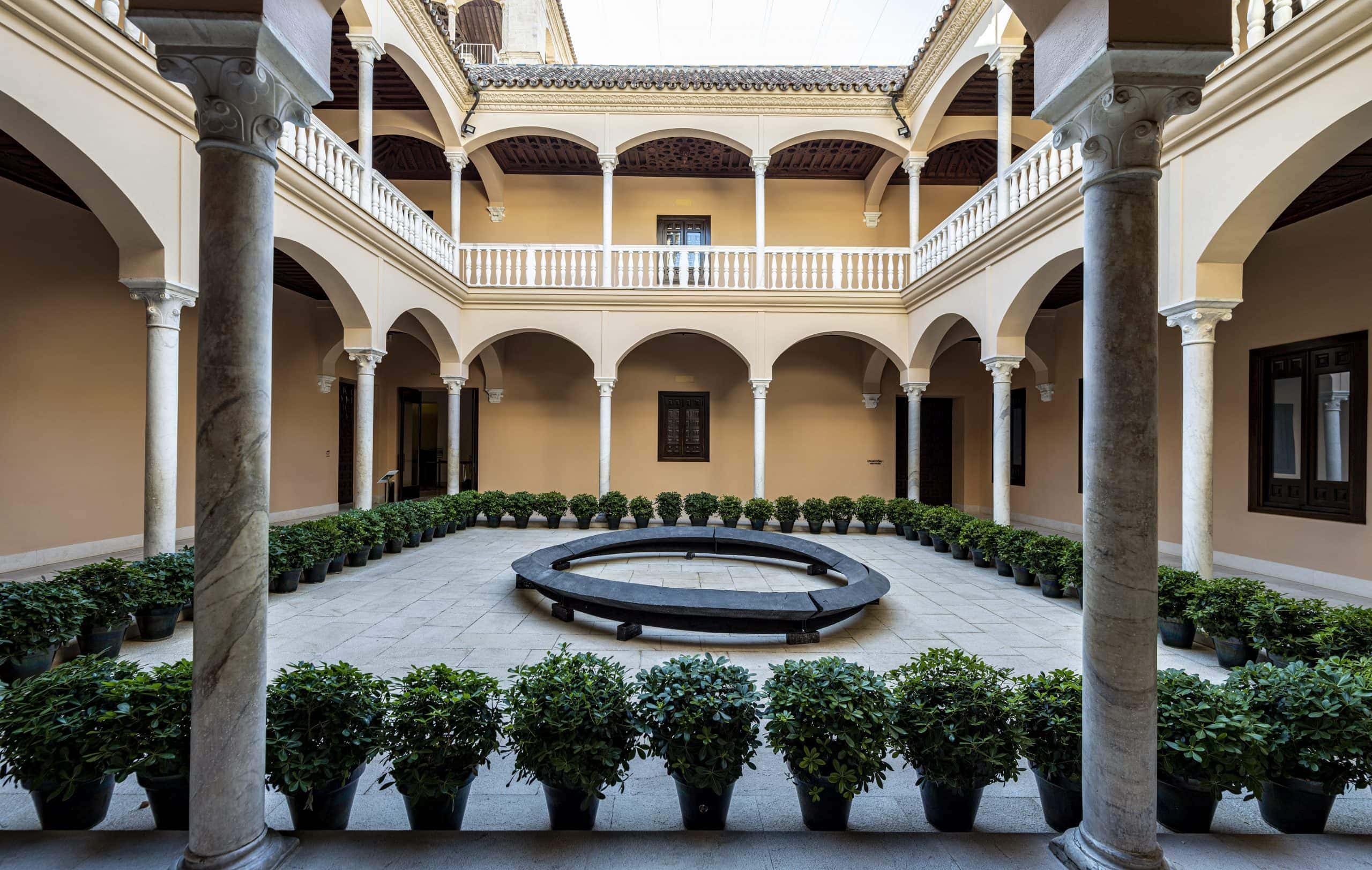 a courtyard with a circular bench and potted plants