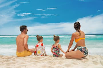 a man and woman sitting on a beach with two children