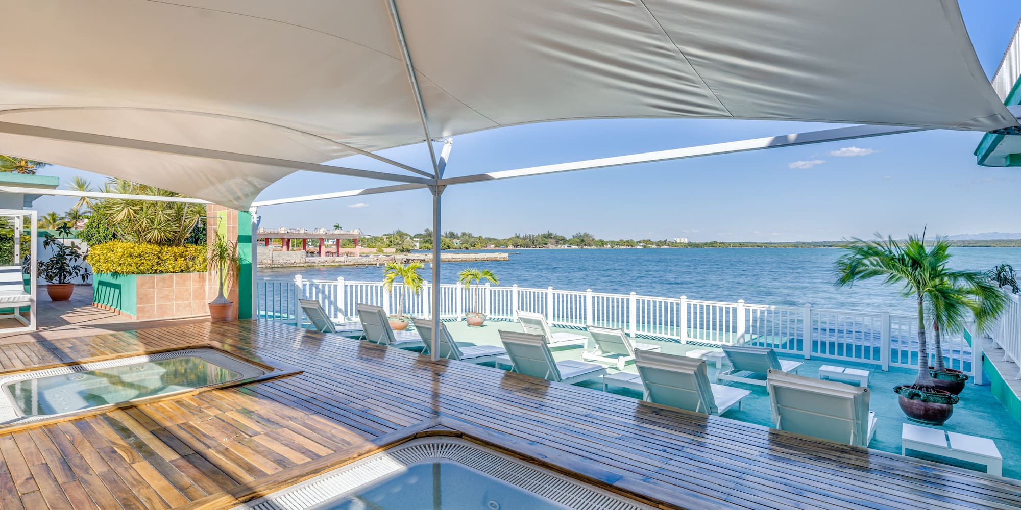 a hot tub with a deck and chairs on a deck overlooking a body of water