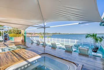 a hot tub with a deck and chairs on a deck overlooking a body of water