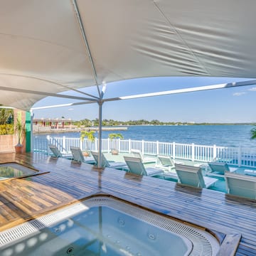 a hot tub with a deck and chairs on a deck overlooking a body of water