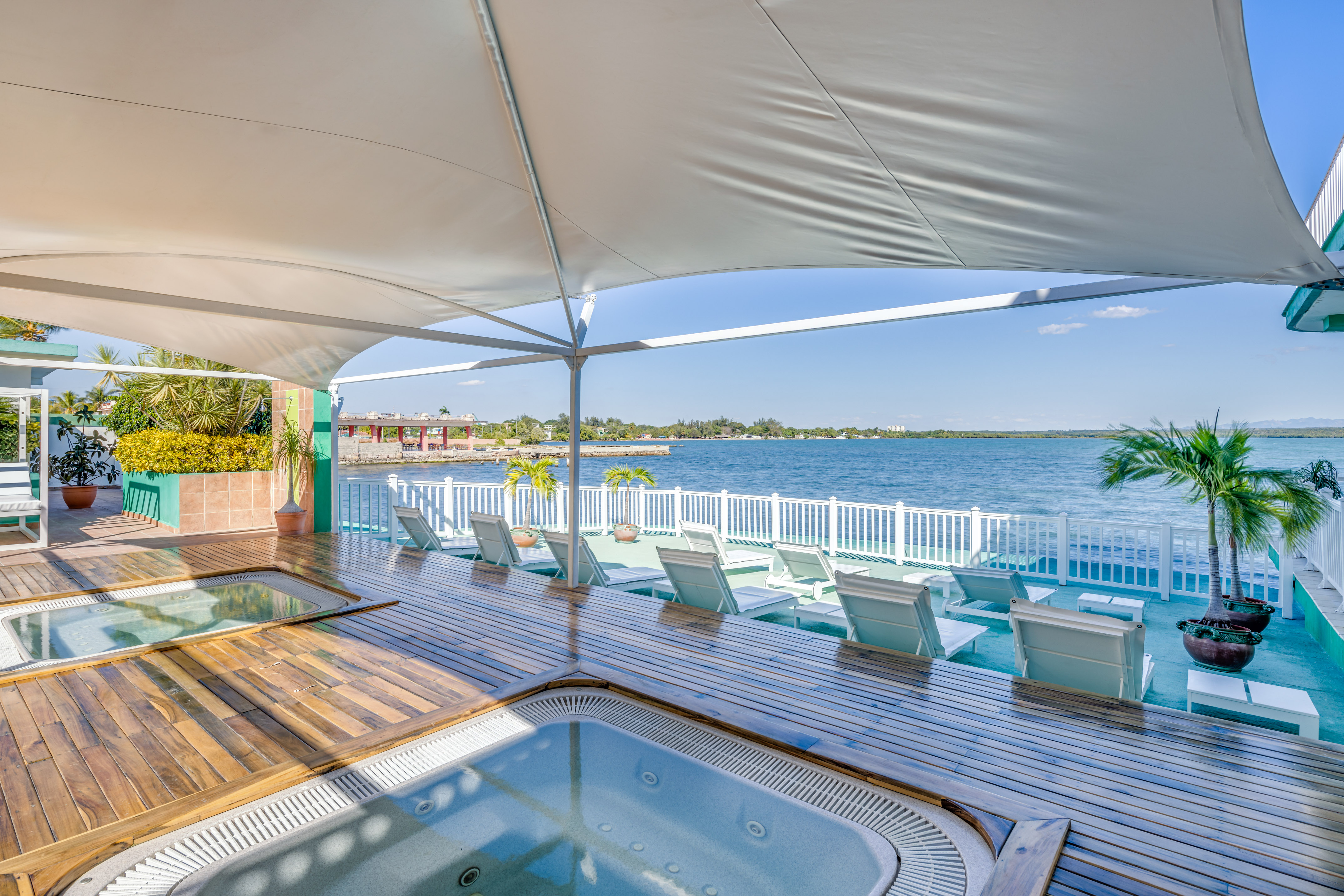 a hot tub with a deck and chairs on a deck overlooking a body of water