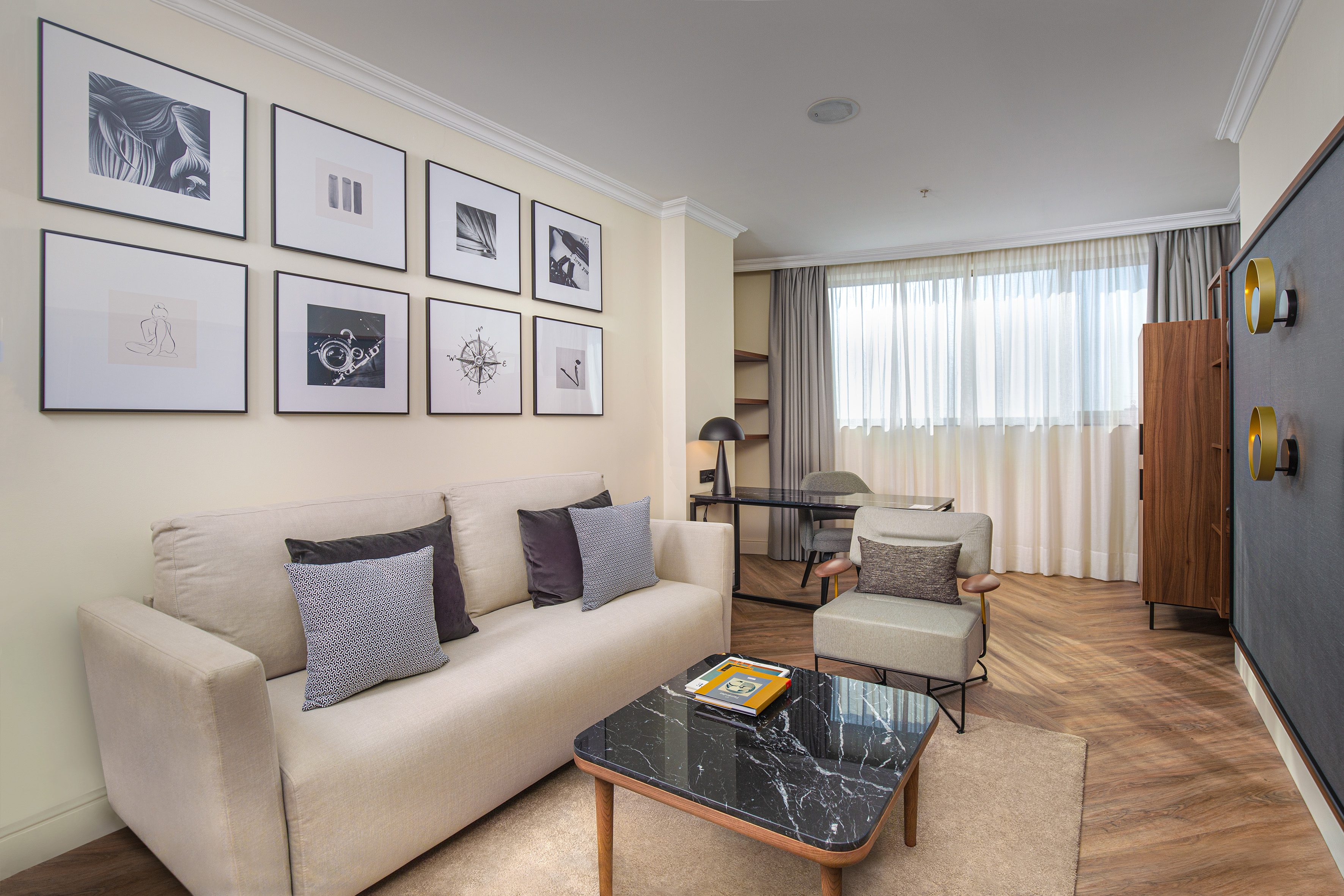 Modern living room with light sofa, marble coffee table, and framed gallery wall art.