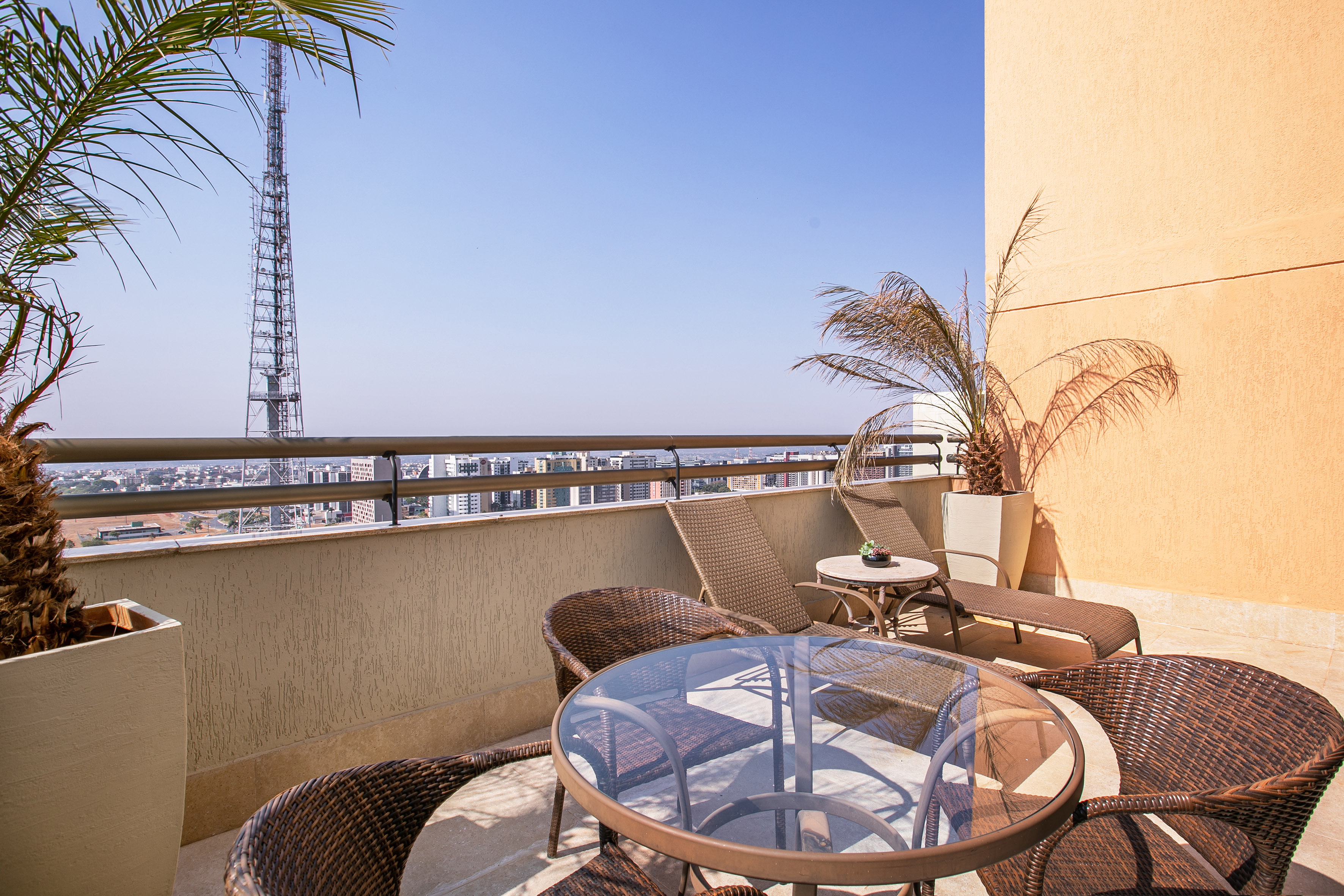 Apartment balcony with patio furniture, city skyline, and communications tower.