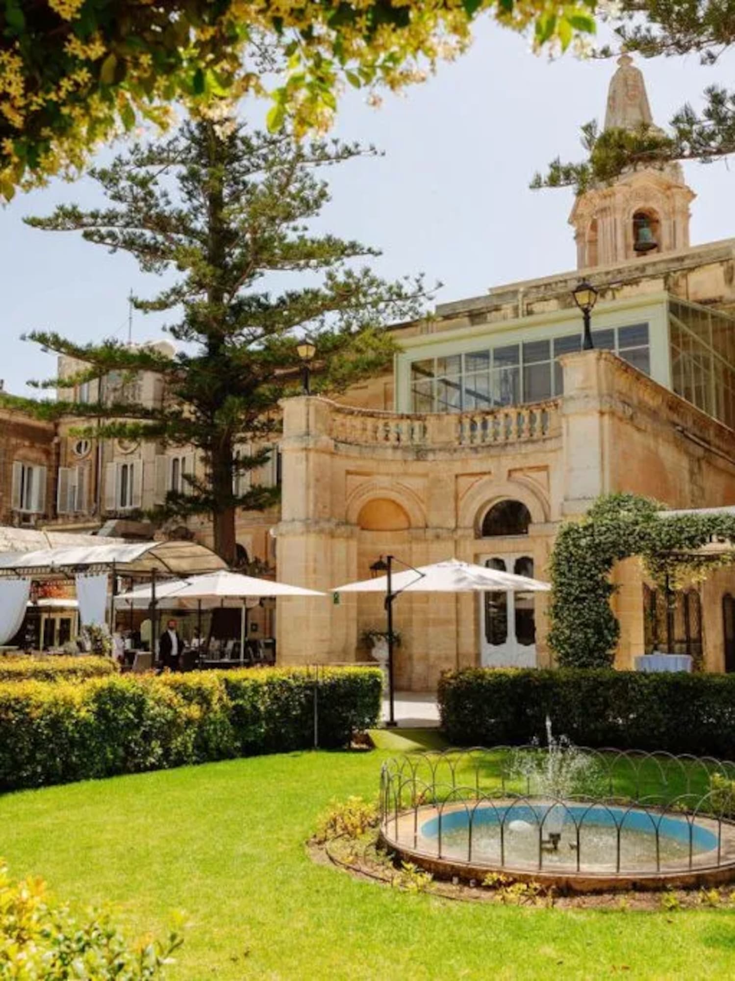 Historic villa garden with fountain, outdoor event setup, and flowering arch.