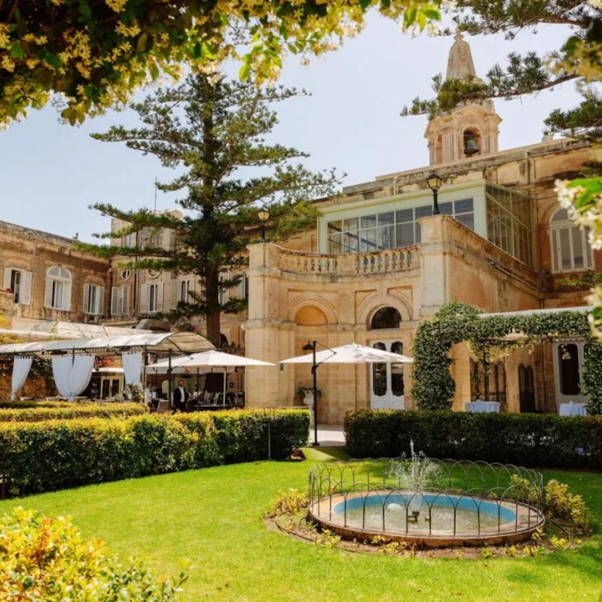 Historic villa garden with fountain, outdoor event setup, and flowering arch.