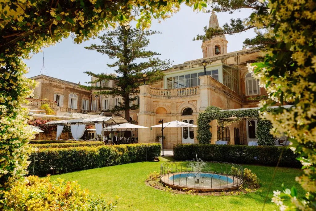Historic villa garden with fountain, outdoor event setup, and flowering arch.