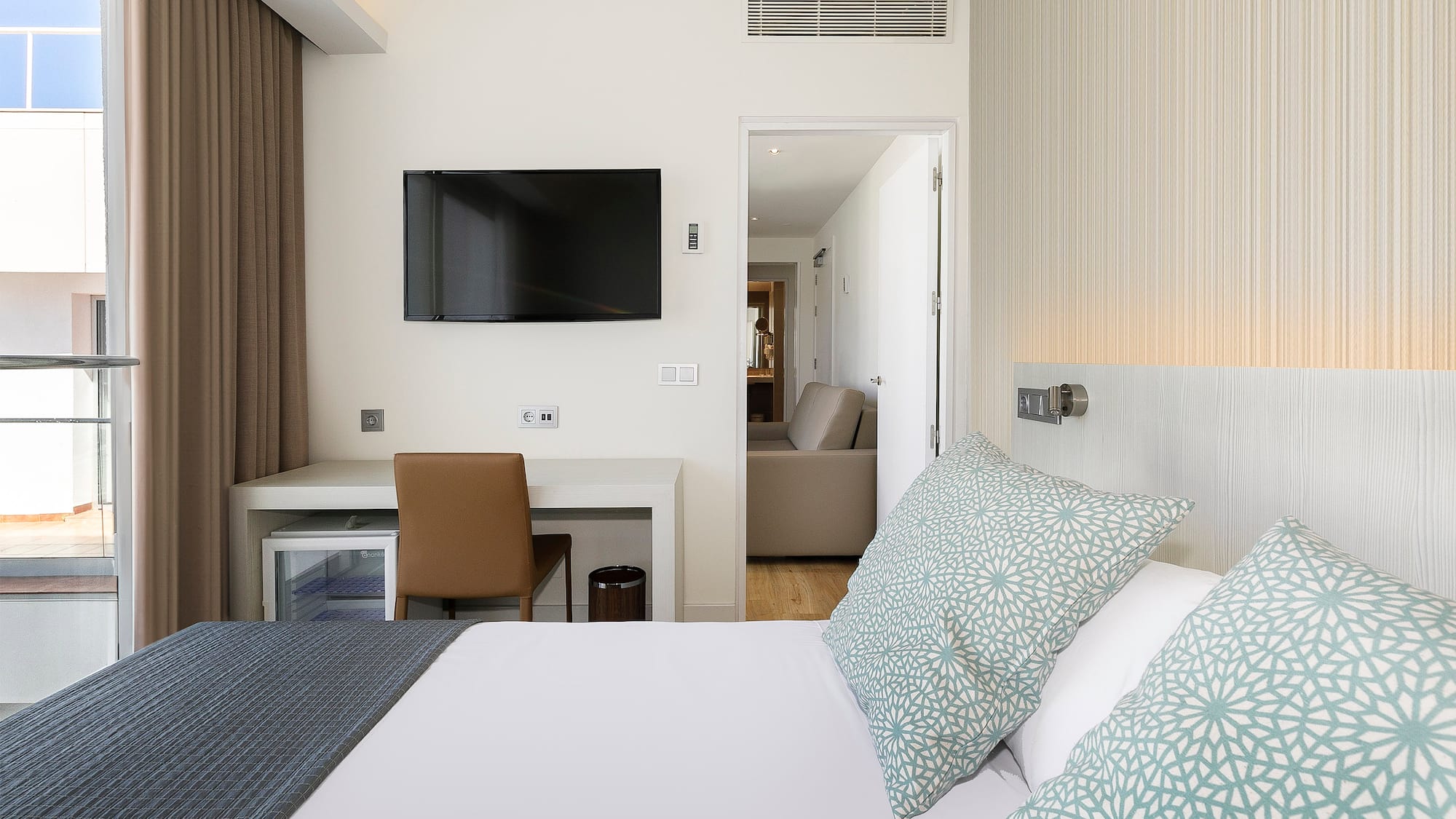 a bed with pillows and a tv on the wall