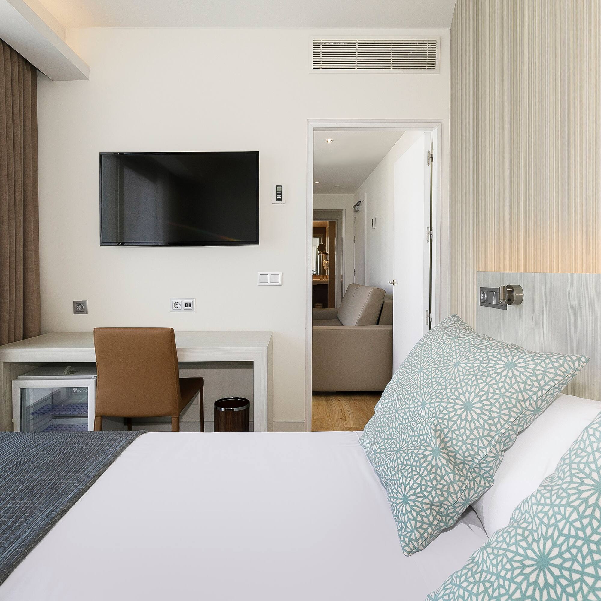 a bed with pillows and a tv on the wall