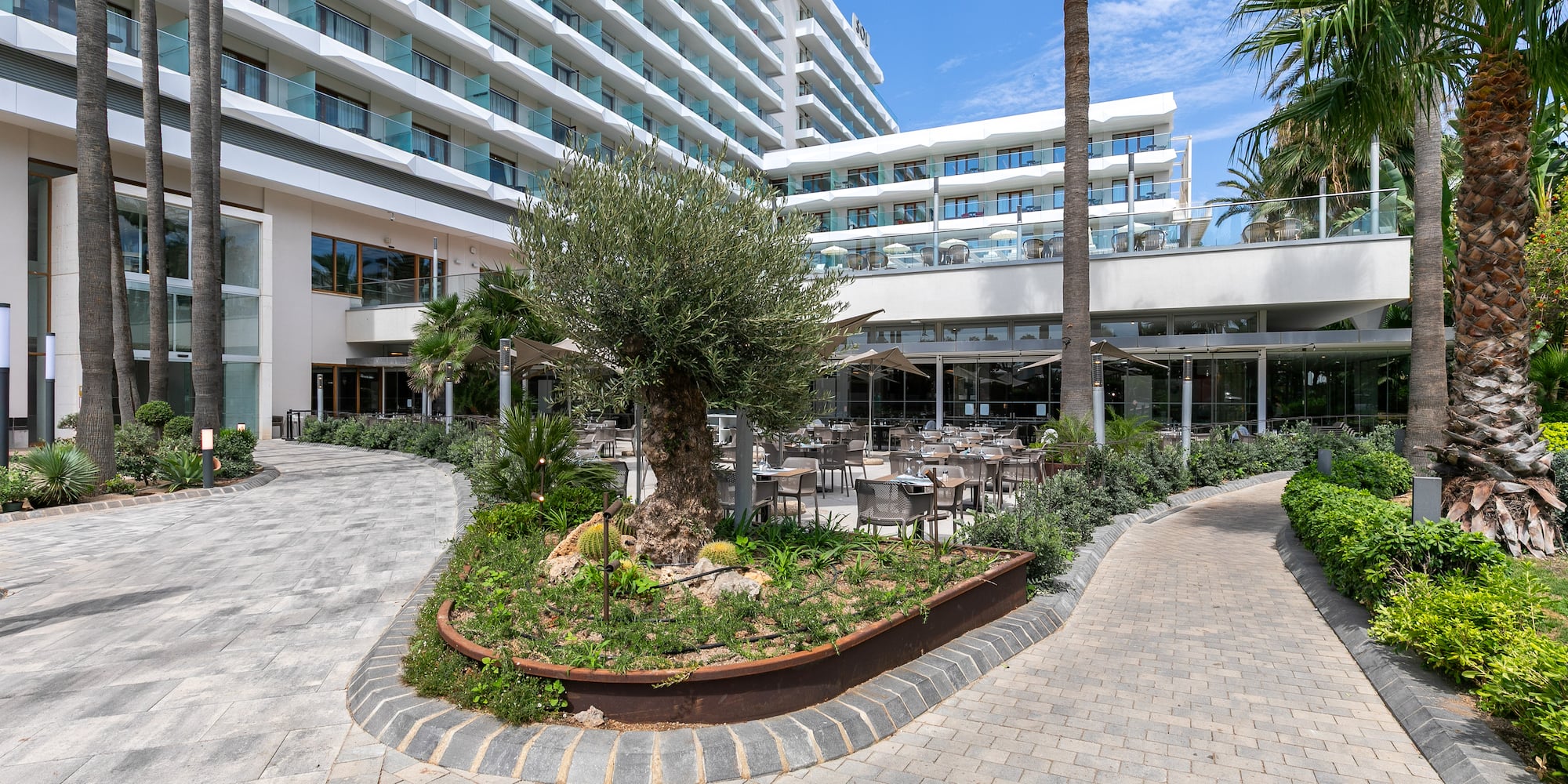 a courtyard of a hotel with palm trees and a large building