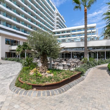 a courtyard of a hotel with palm trees and a large building